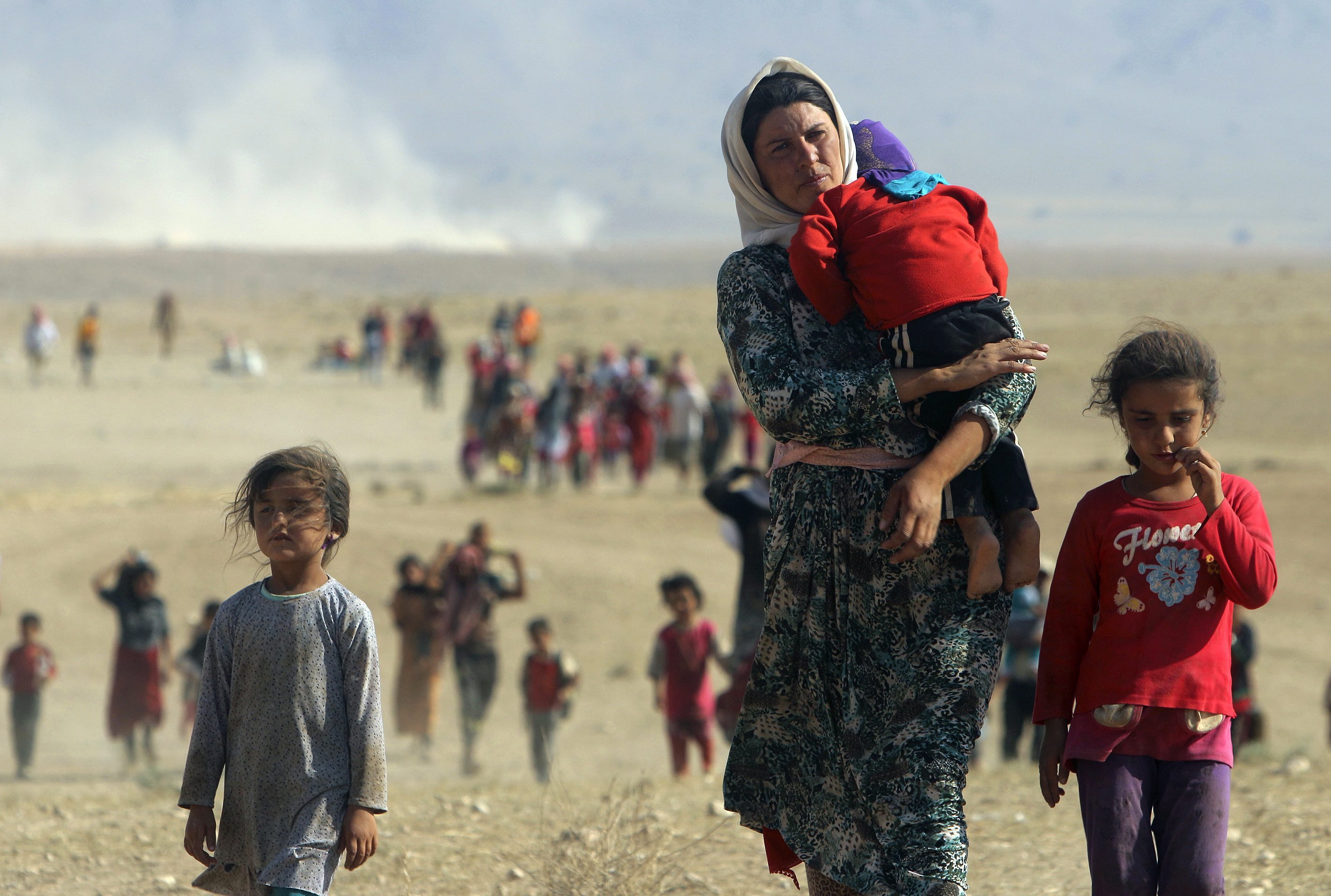 Displaced people from the minority Yazidi sect, fleeing violence from forces loyal to the Islamic State in Sinjar town, walk towards the Syrian border, on the outskirts of Sinjar mountain, near the Syrian border town of Elierbeh of Al-Hasakah Governorate on August 11, 2014.
