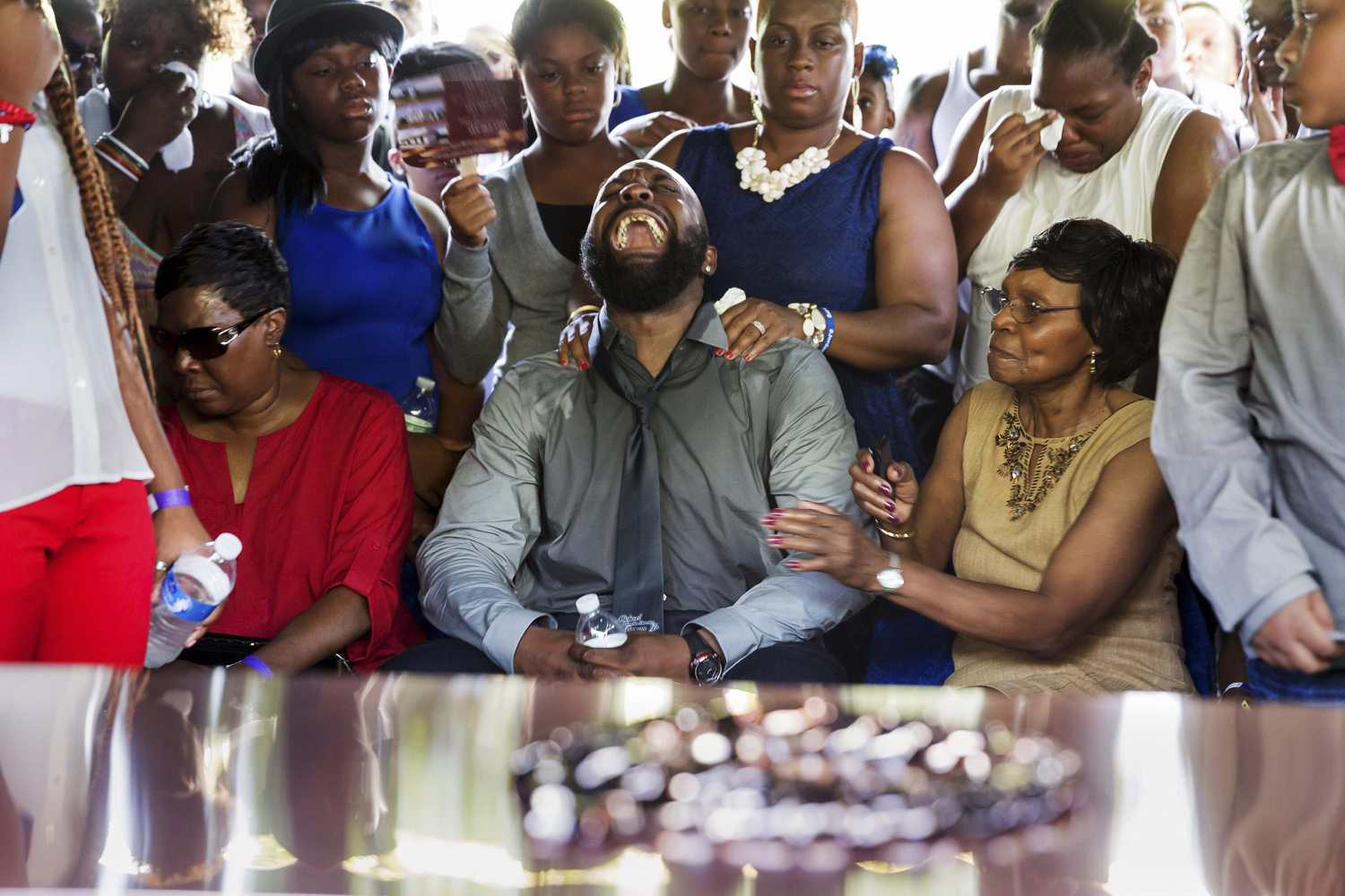 Michael Brown Sr. yells out as his son's casket is lowered into the ground at St. Peter's Cemetery in St. Louis
