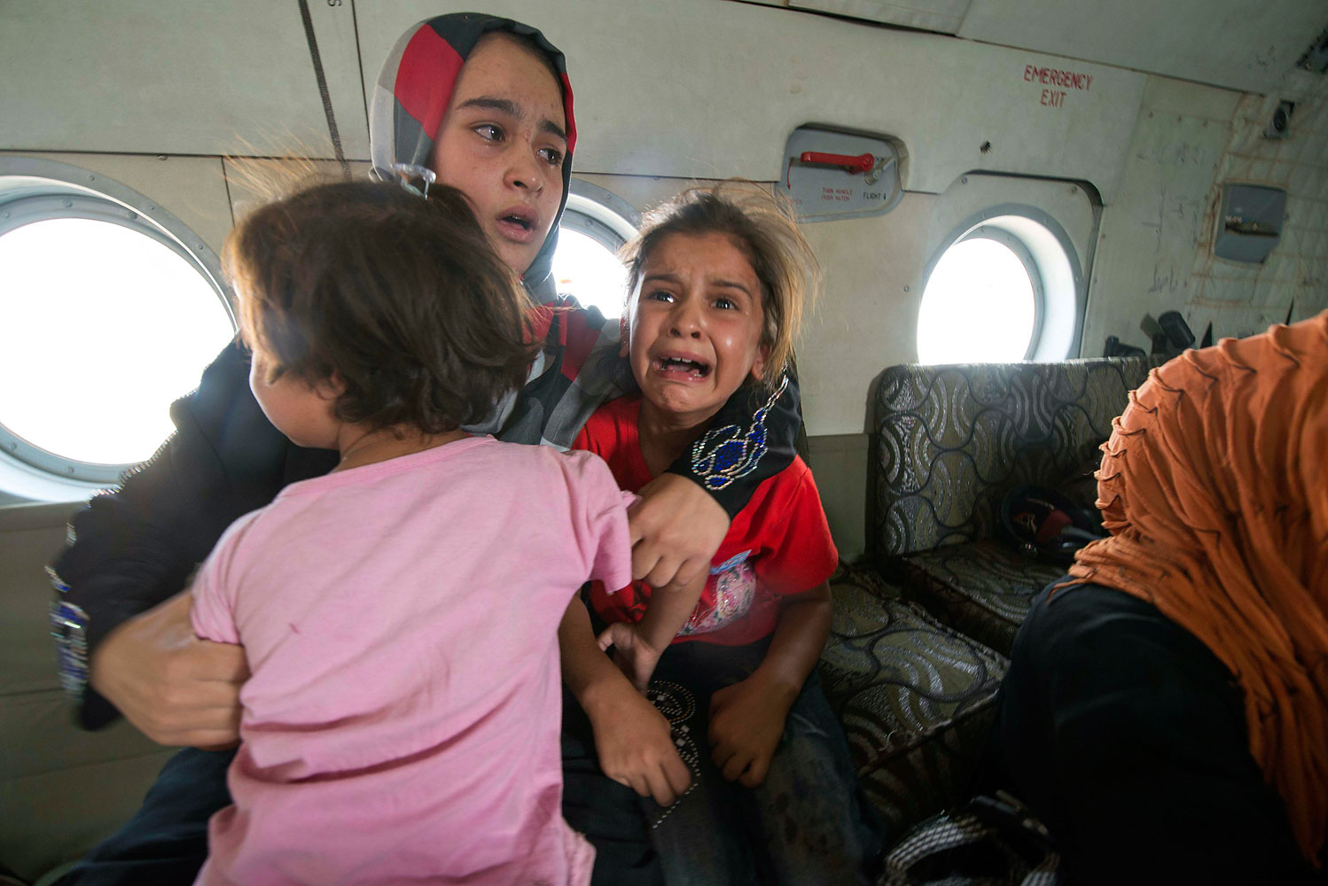 A woman and children react in a military helicopter after being evacuated by Iraqi forces from Amerli