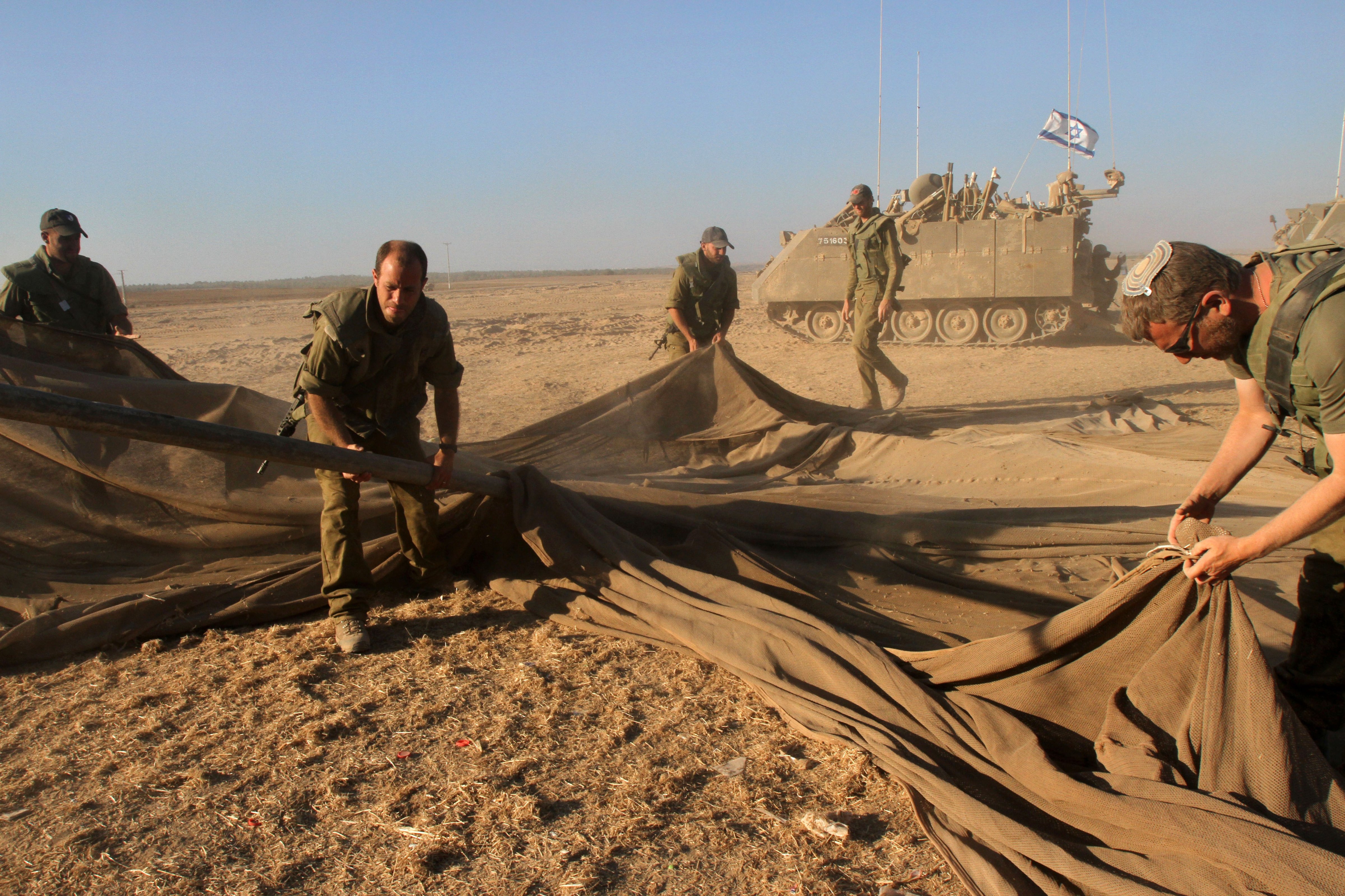 Israeli soldiers fold their equipment along the border between Israel and the Gaza Strip after they pulled out from the Gaza Strip  on Aug. 3, 2014 (Gil Cohen Magen—AFP/Getty Images)