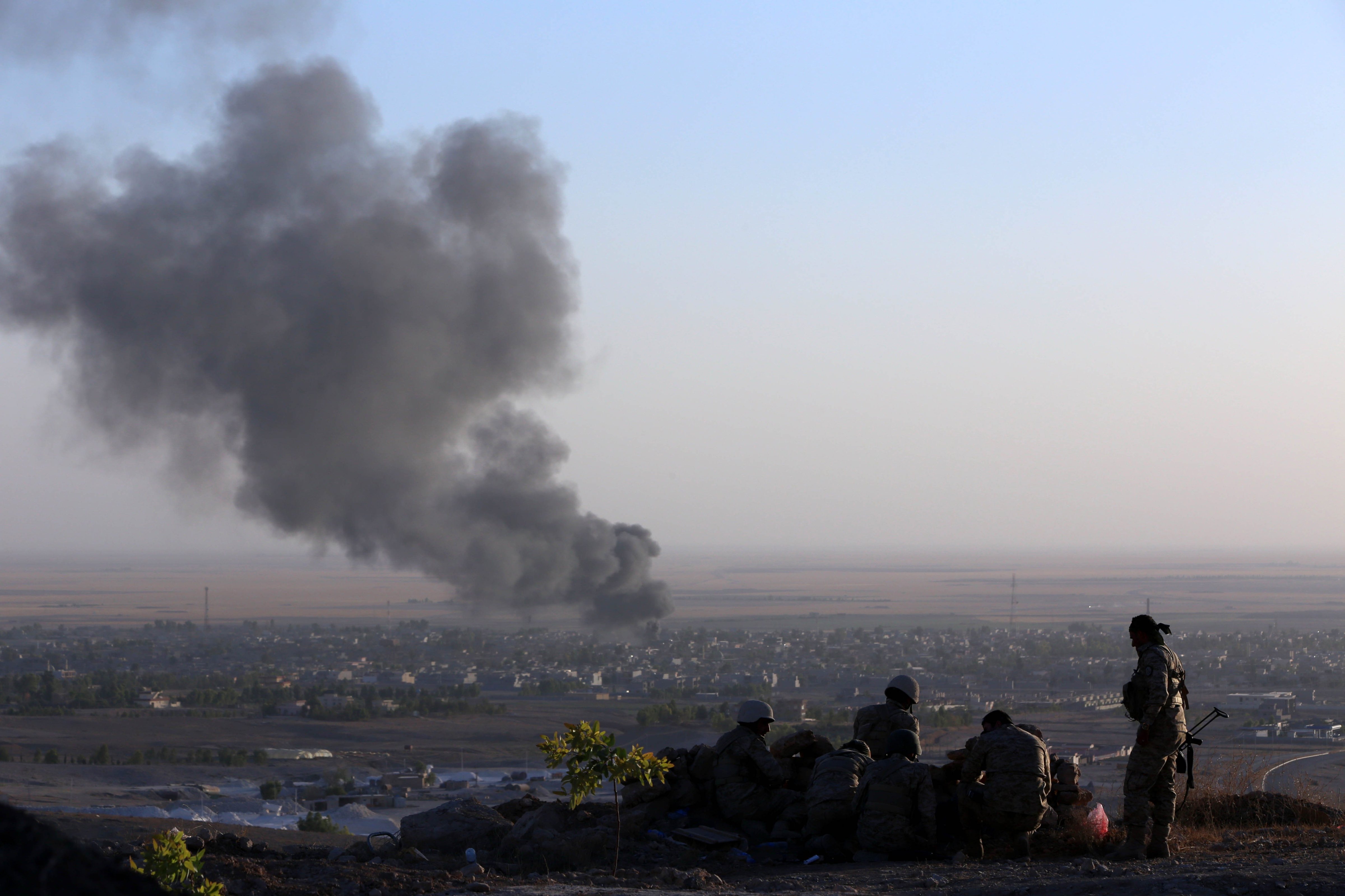 Iraqi Kurdish Peshmerga fighters look on as smoke billows from the town Makhmur, about 175 miles north of Baghdad, during clashes with ISIS militants on August 9, 2014 (Safin Hamed—AFP/Getty Images)