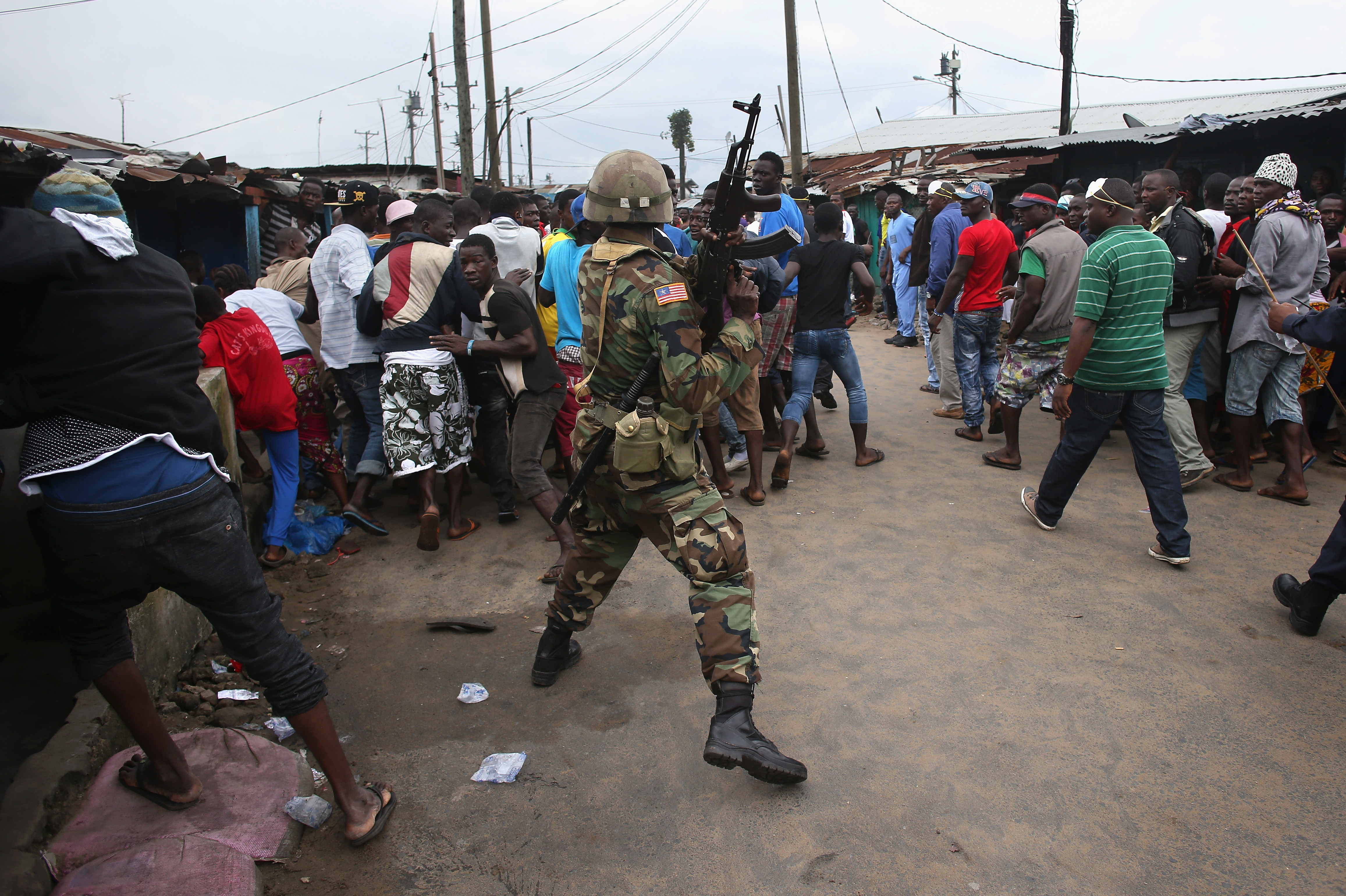 A Liberian Army soldier, part of the Ebola Task Force, pushes back local residents while enforcing a quarantine on the West Point slum on August 20, 2014 in Monrovia, Liberia. (John Moore—Getty Images)