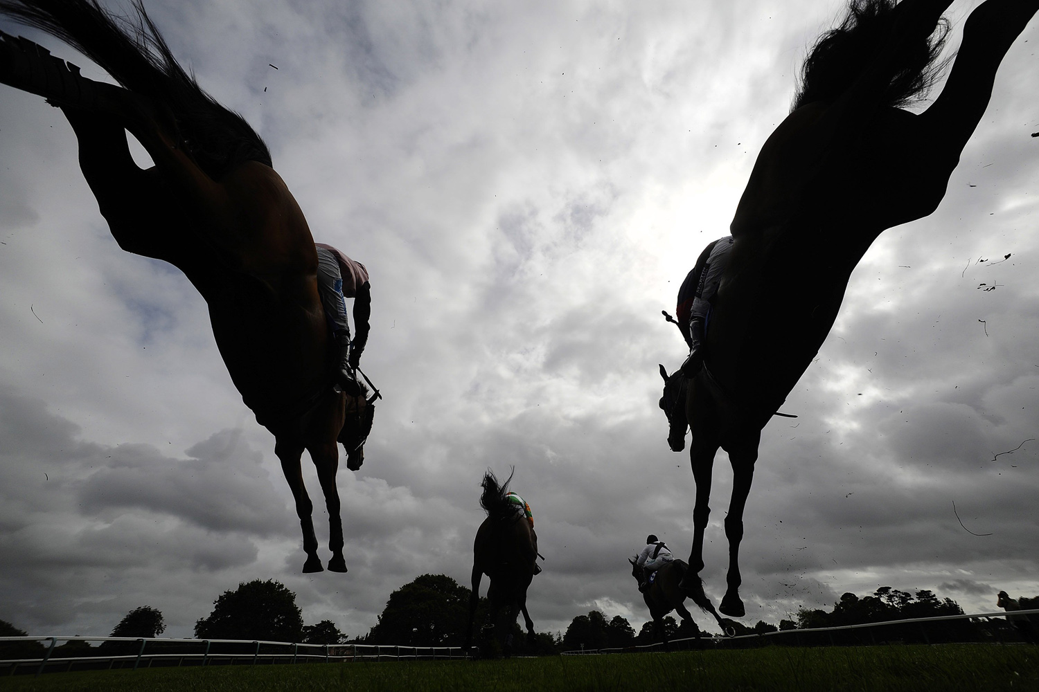 Aug. 28, 2014. Runners clear a fence in The £500 Permanent Money Backs Handicap Steeple Chase at Fontwell racecourse in Fontwell, England.