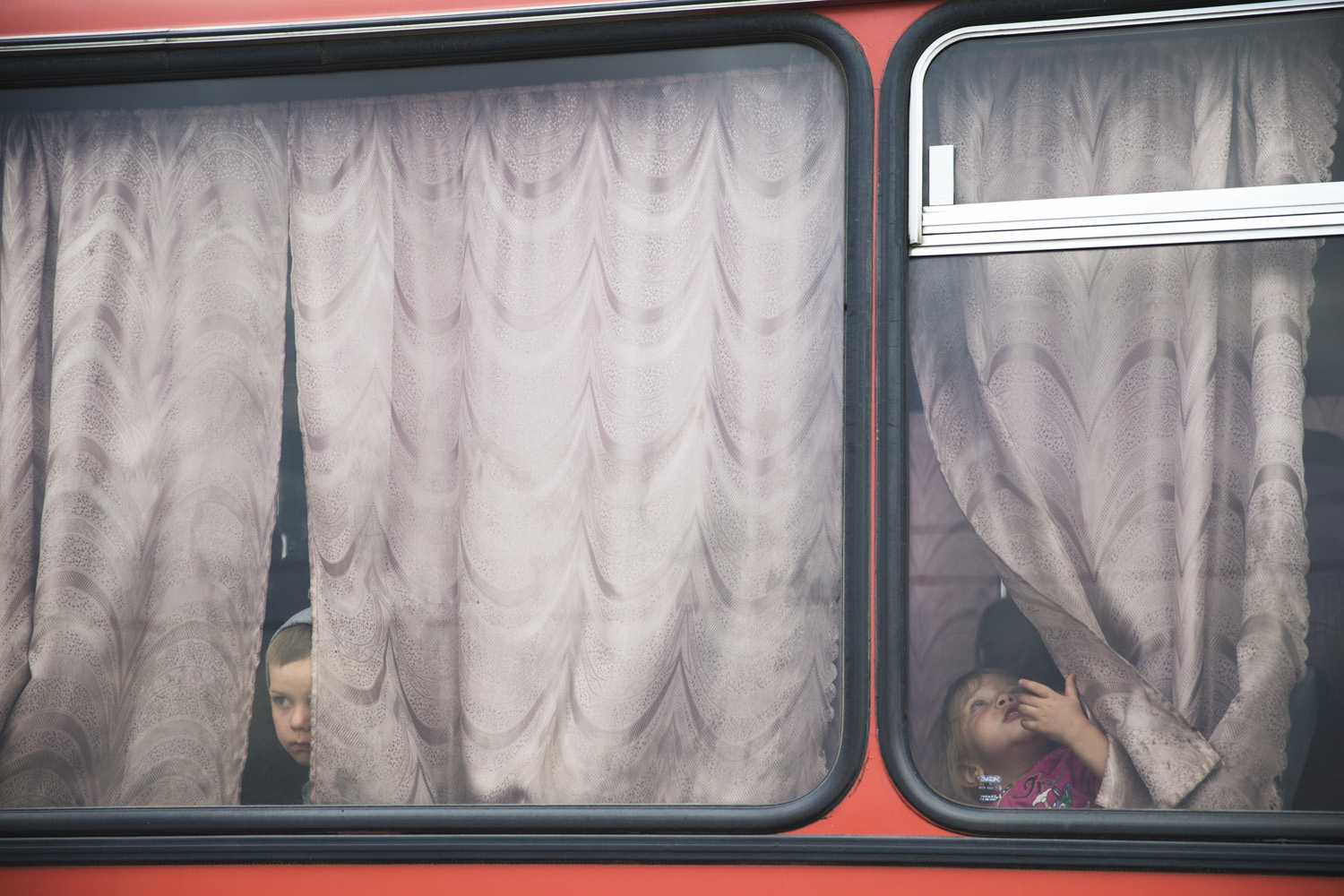 Aug. 18, 2014. Children look out from a bus before leaving for the train station, ahead of a train journey to the Russian Siberian city of Irkutsk where they are being relocated, at a refugee camp set up by the Russian Emergencies Ministry about 10 kilometers (6 miles) from the Russia-Ukrainian border, near Donetsk, Rostov-on-Don region, Russia.