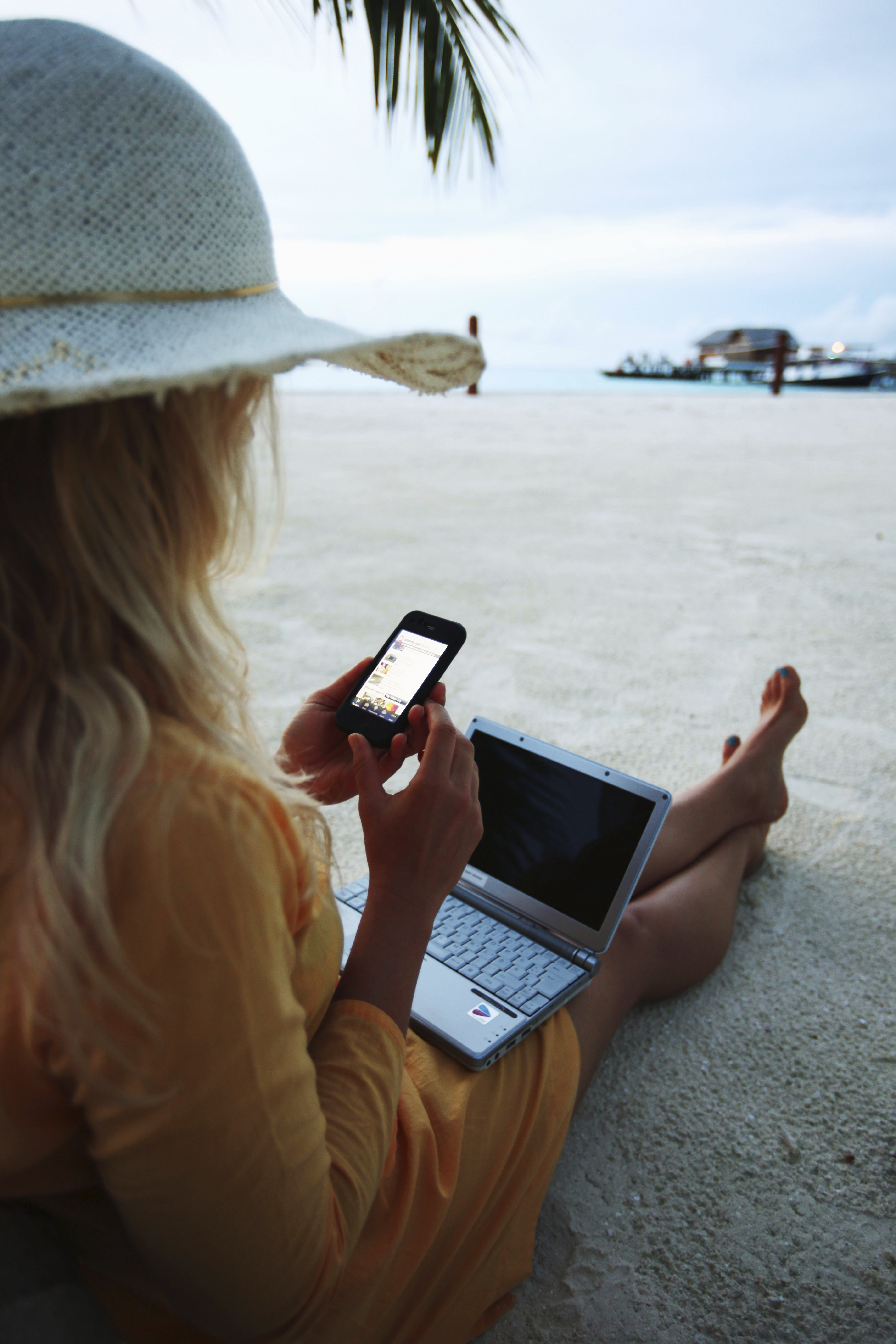 Woman sitting on Villingili beach, working with a notebook and mobile phone, surfing in the internet. The island is owned by the luxurious Shangri-La's Villingili Resort and Spa Hotel on September 27, 2009 in Male, Maldives. (EyesWideOpen--Getty Images)