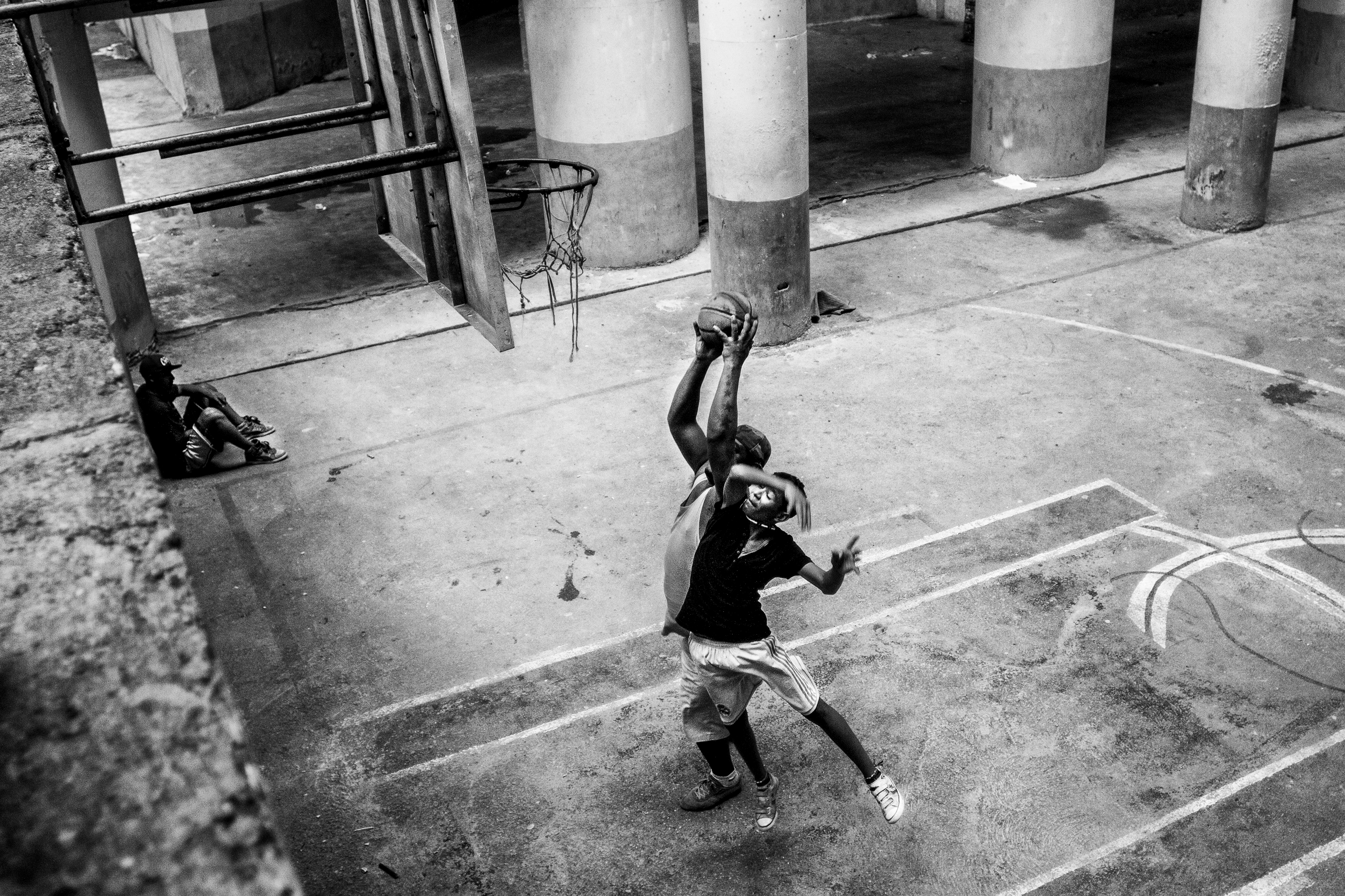 A man and a boy play basketball on a makeshift court on the ground floor of the tower, which was supposed to become an auditorium