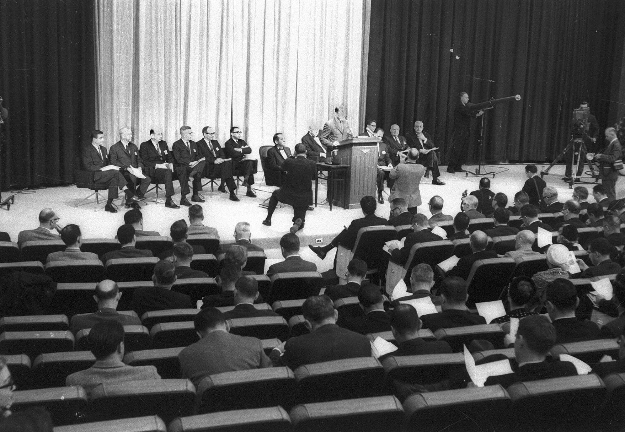 U.S. Surgeon General Luther Terry, at rostrum, answers questions on a landmark report on the dangers of smoking during a Jan. 11, 1964 news conference in Washington.  Members of his advisory committee sit behind him, with Dr. Emmanuel Farber sixth from left, with arms folded (ASSOCIATED PRESS—ASSOCIATED PRESS)