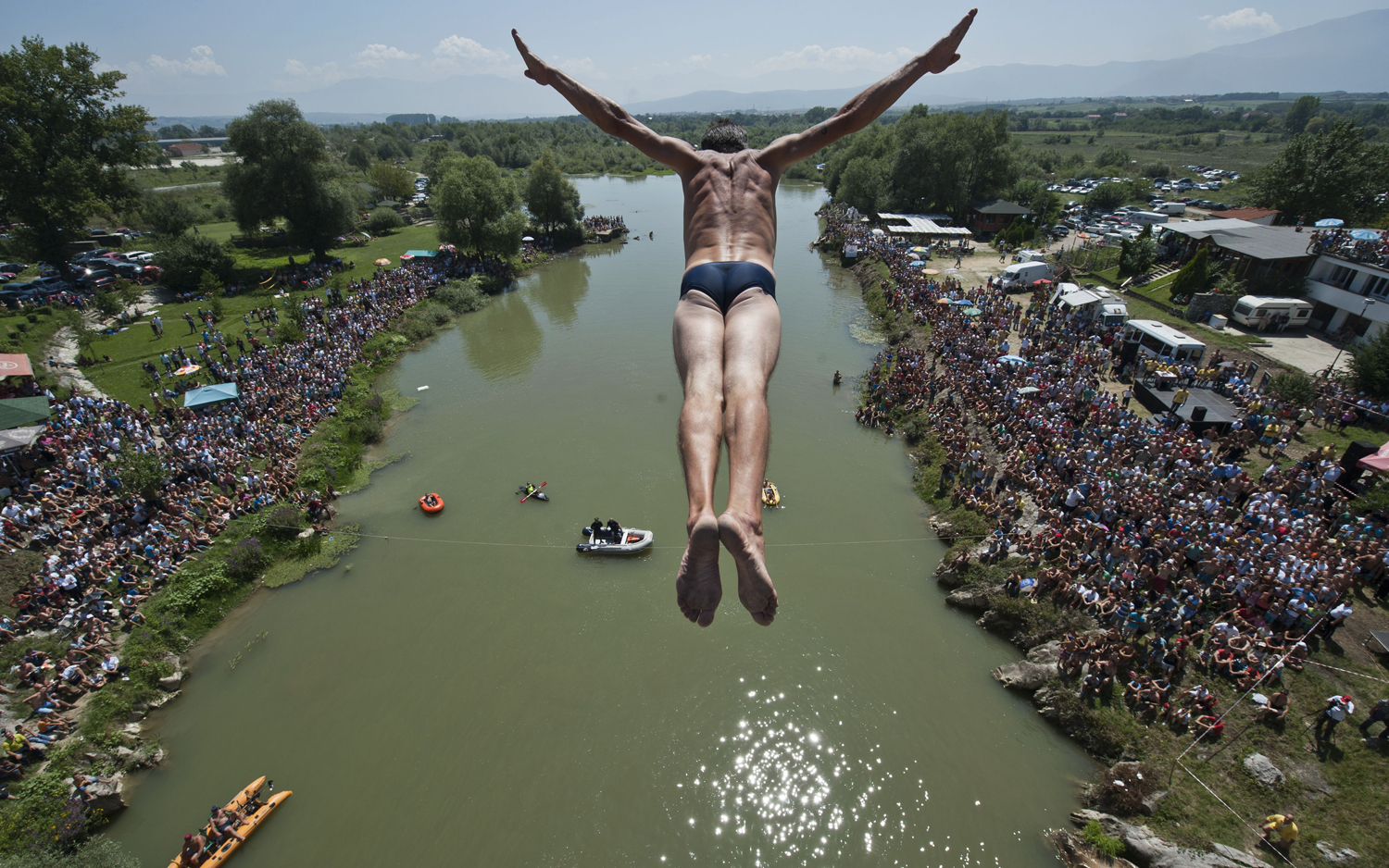 Aug. 10, 2014. Spectators watch as a diver Sali Riza Grancina performs the winning jump from the Ura e Shenjte bridge during the traditional annual high diving competition, near the town of Gjakova, Kosovo.