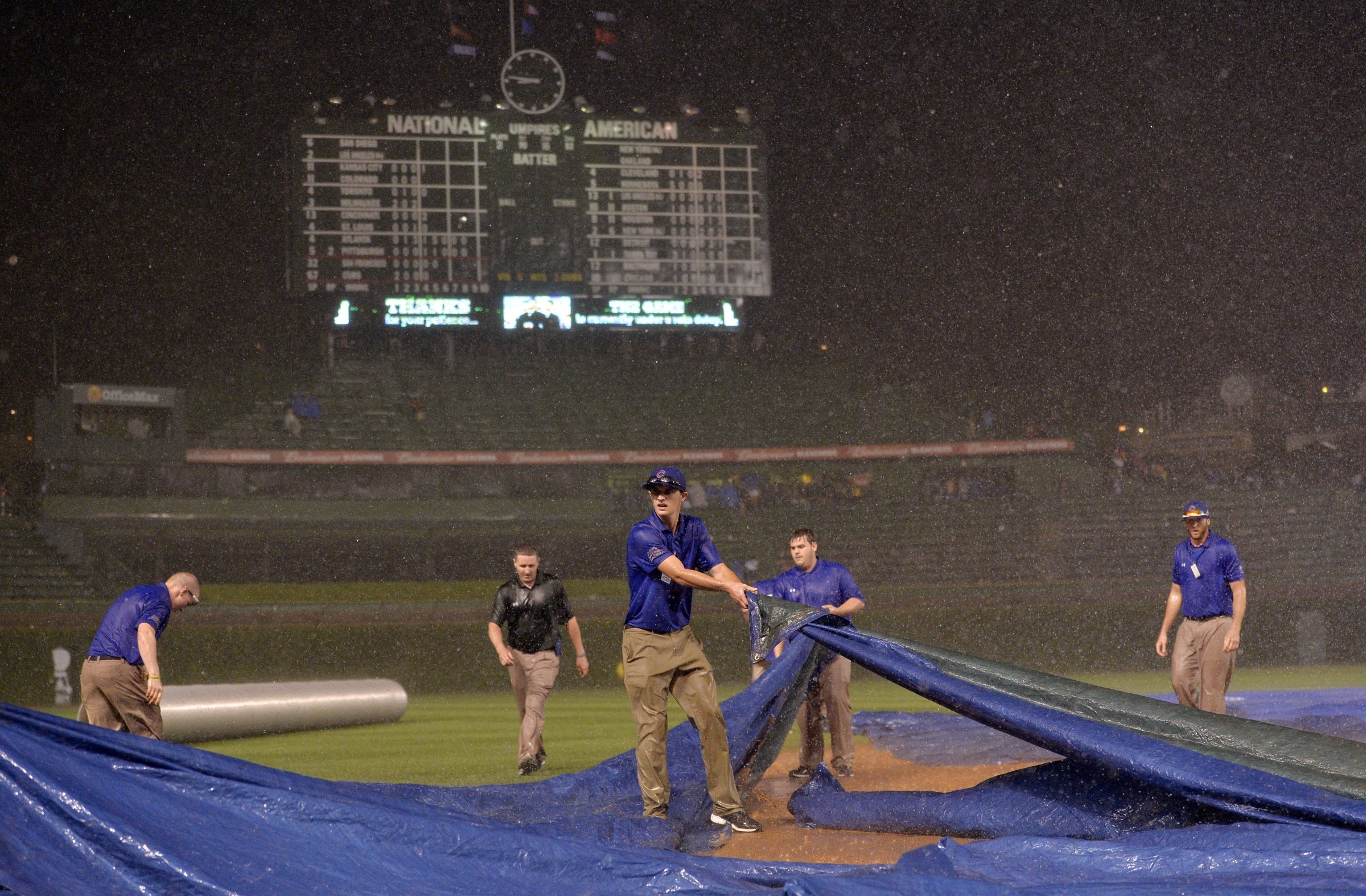 Chicago Cubs ground crew members struggle to get the tarp on the field as rain falls during the fifth inning of the Chicago Cubs game against the San Francisco Giants at Wrigley Field on August 19, 2014 in Chicago.