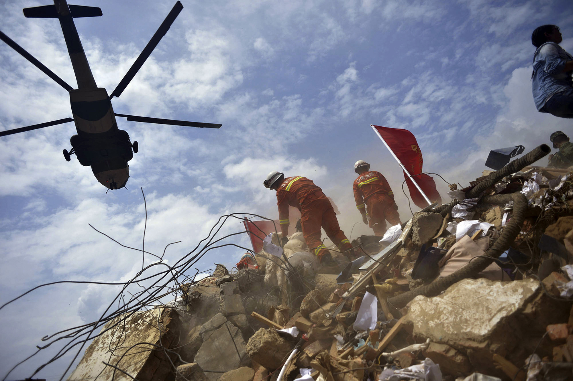 A helicopter flies over rescue workers at the epicenter of Sunday's earthquake that struck the town of Longtoushan in Ludian County in southwest China's Yunnan Province, Aug. 4, 2014.