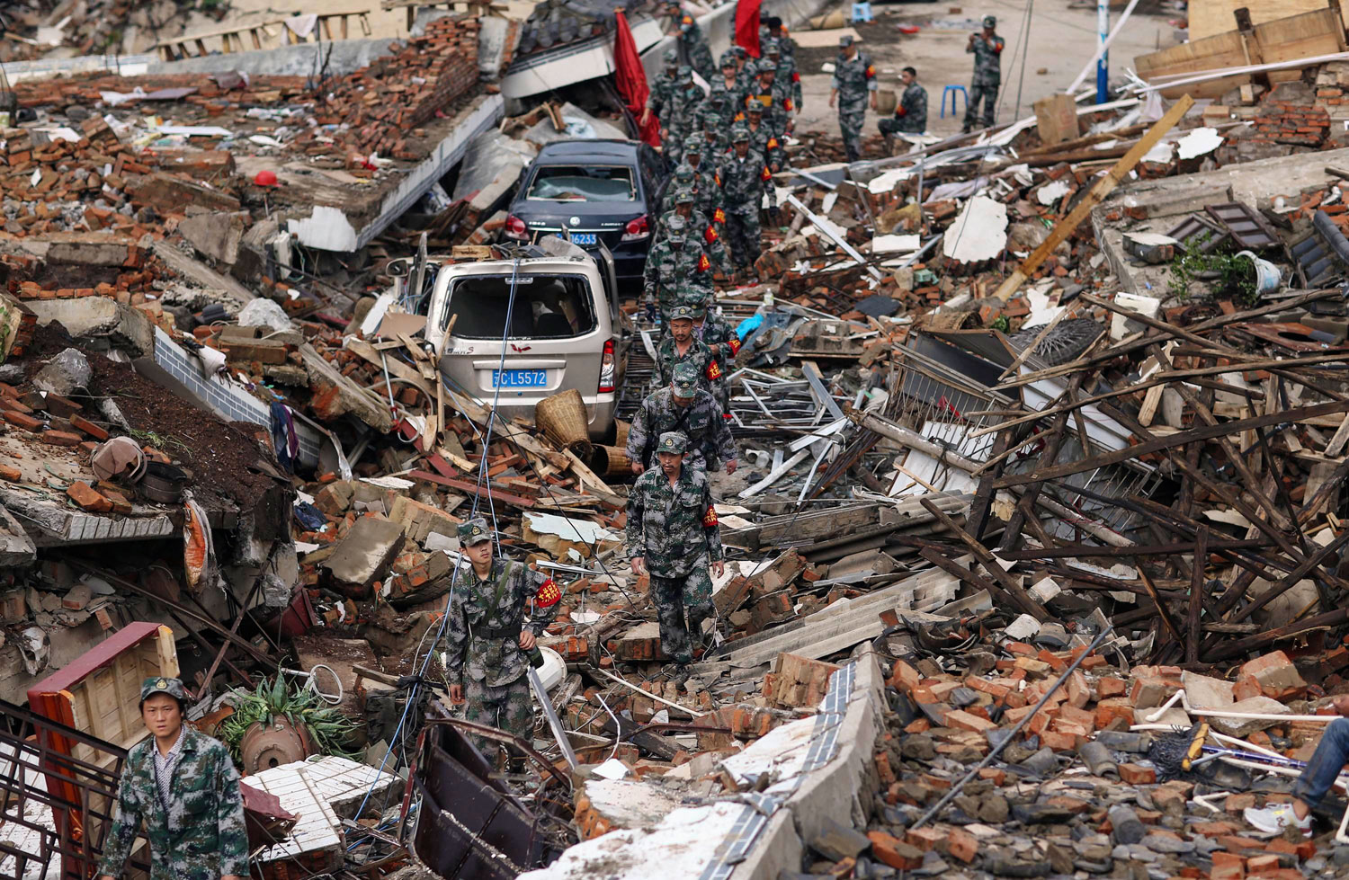Rescuers search for survivors as they walk among debris of collapsed buildings after an earthquake hit Longtoushan township of Ludian county