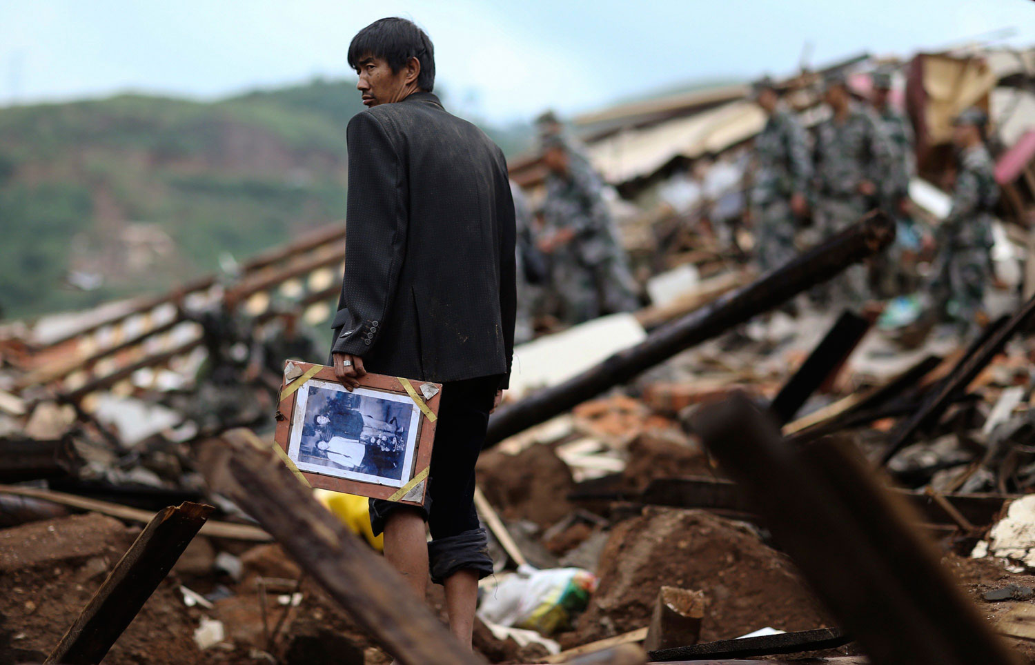 A man holds a picture as he stands among debris after an earthquake hit Longtoushan township of Ludian county