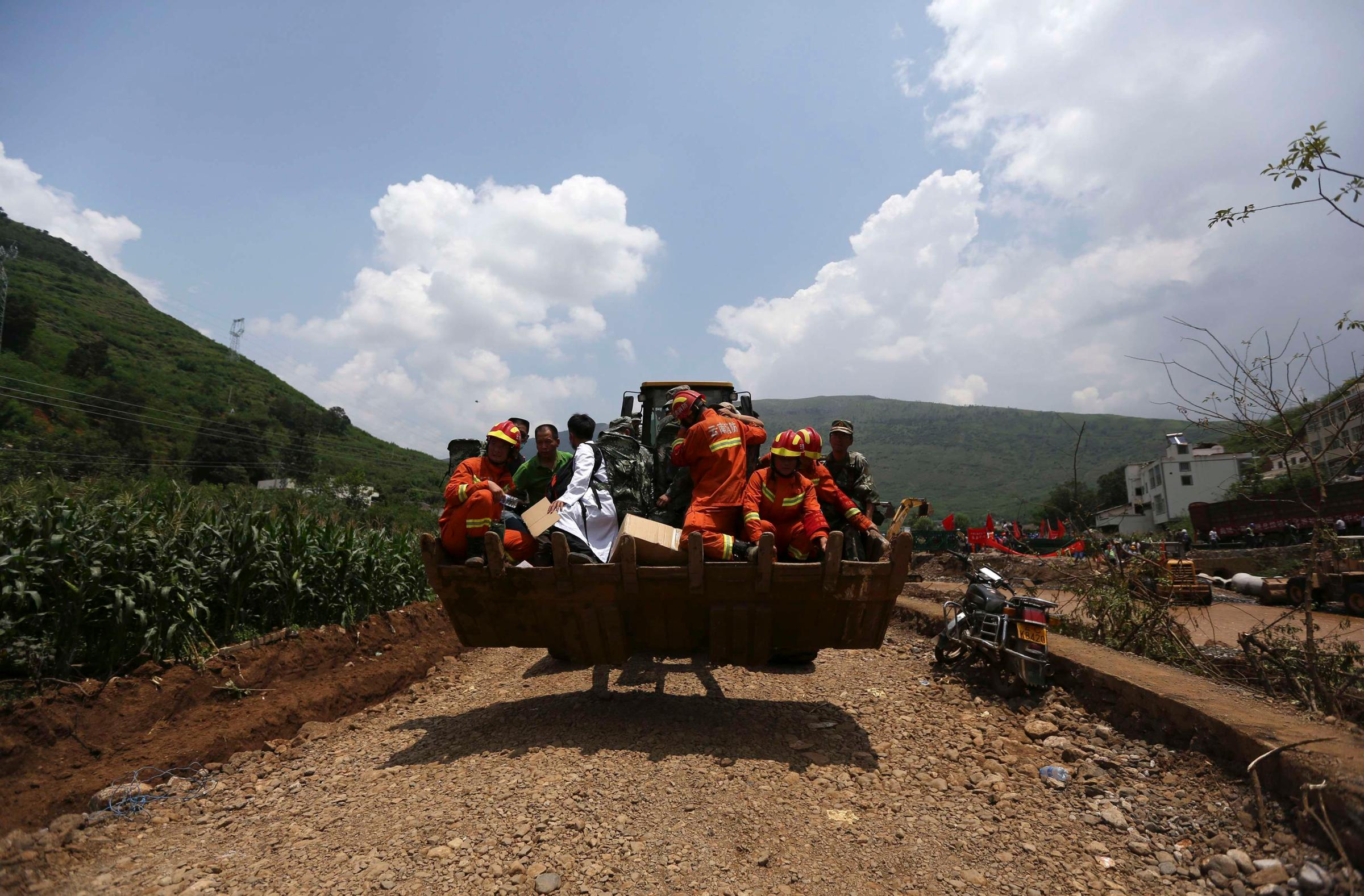 Rescue workers are transported into an earthquake zone on a front loader in Ludian county, Zhaotong, Yunnan province