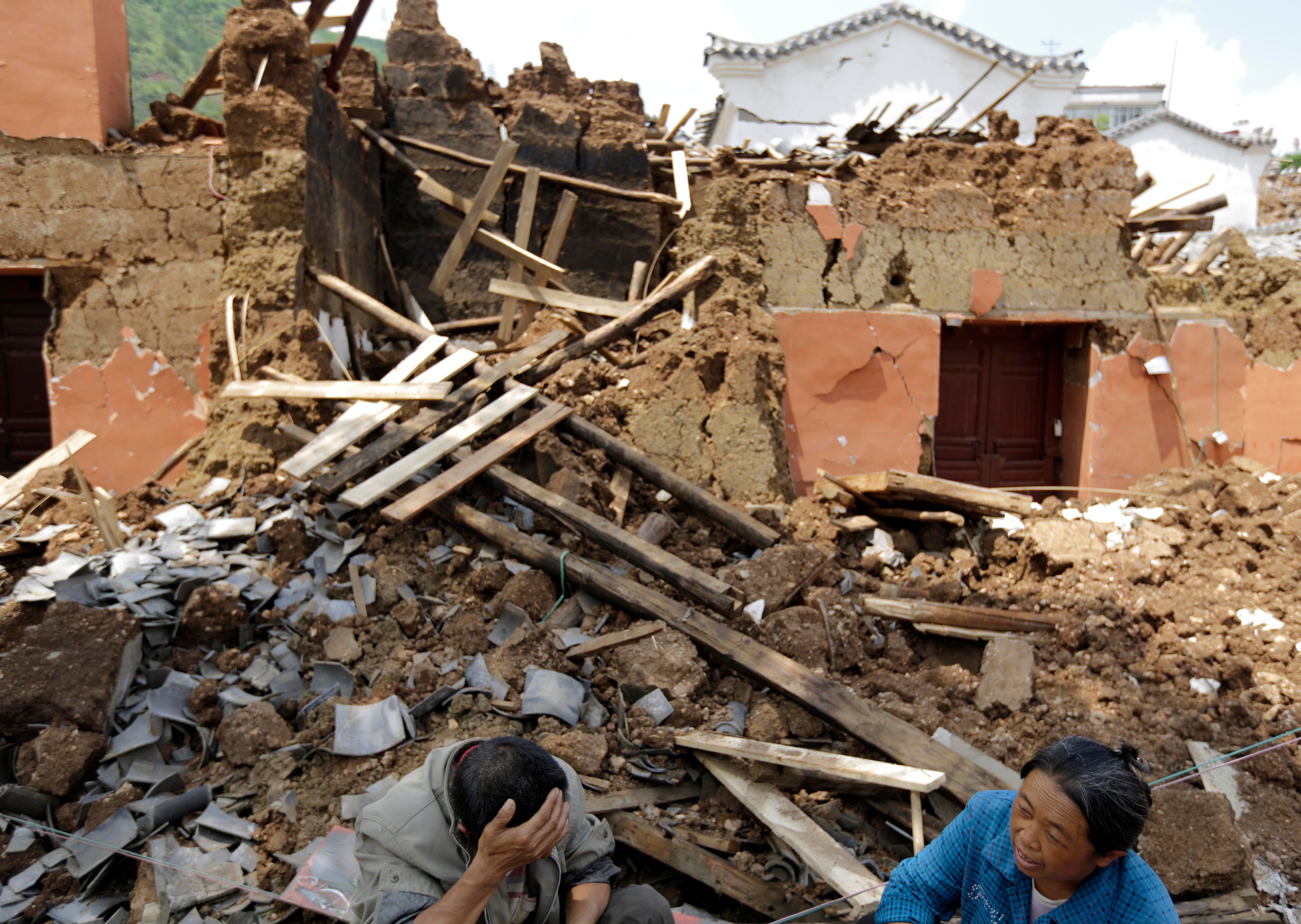 Villagers sit in front of their destroyed house following a massive earthquake in the town of Longtoushan in Ludian County in southwest China's Yunnan Province on Aug. 5, 2014. (Andy Wong—AP)