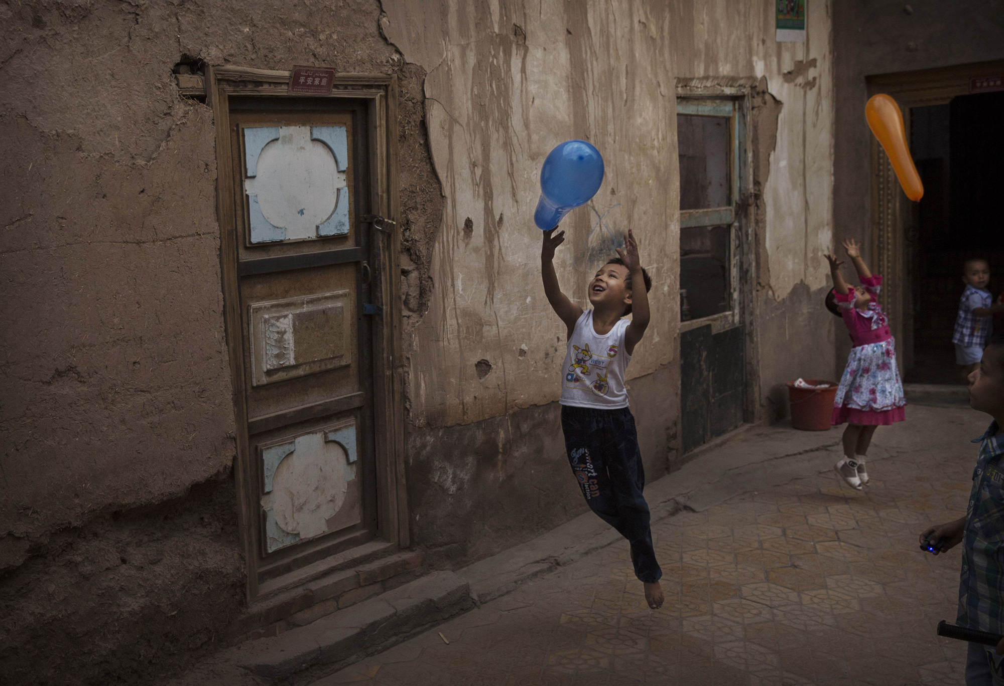 Uyghur children play with balloons on the Eid holiday on July 29, 2014 in alleyway in old Kashgar.