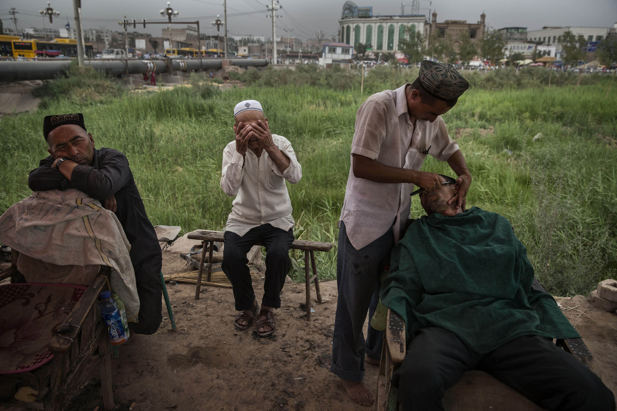 A Uyghur shaves a customer at an outdoor stall before the Eid holiday on July 28, 2014 in old Kashgar.