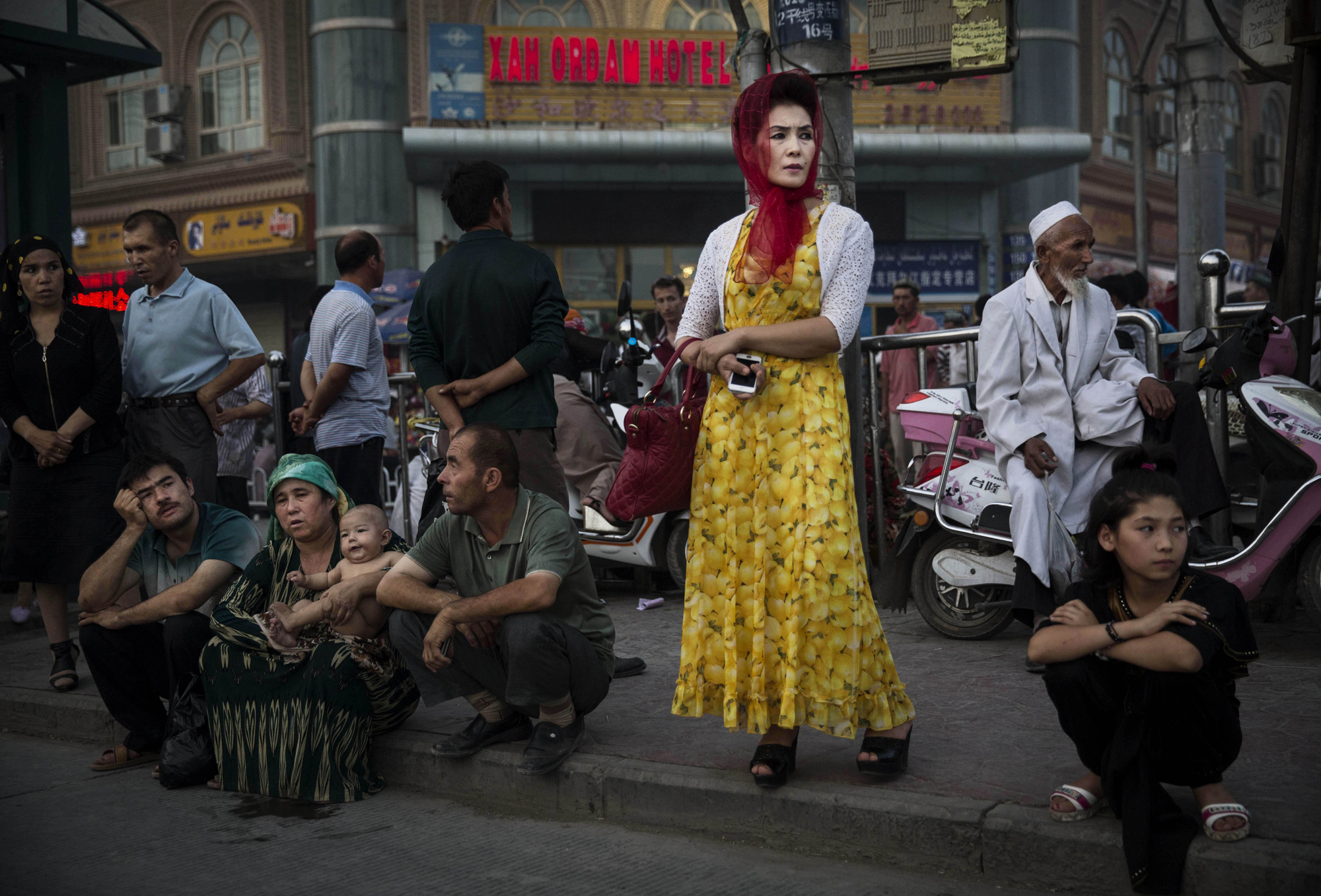 Uyghurs wait at a bus stop on July 27, 2014 in old Kashgar.