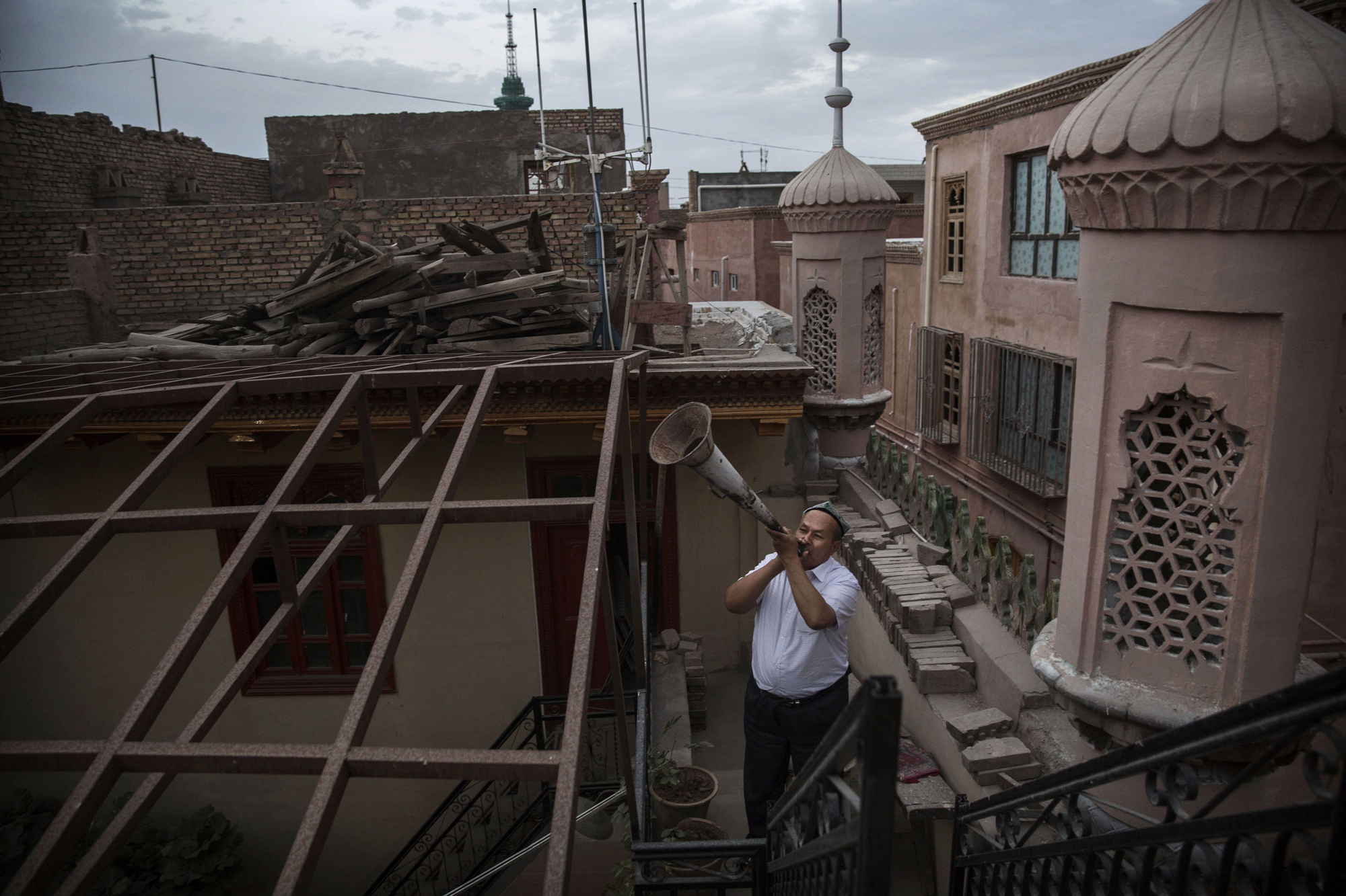 A Uyghur Muslim muezzin uses a bullhorn to call the evening prayers on July 30, 2014 in Kashgar.