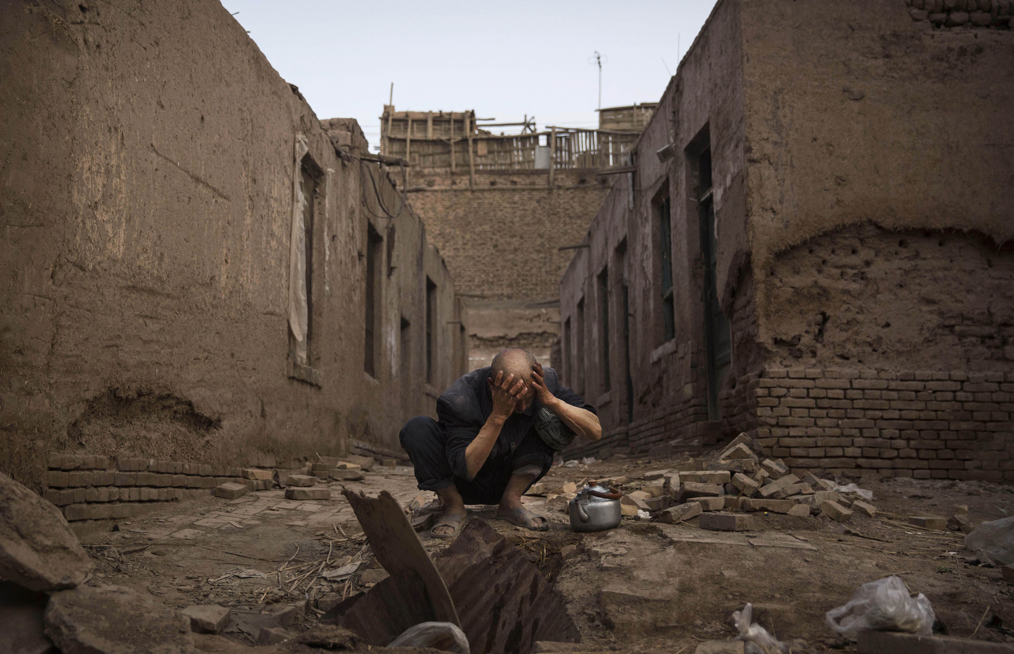 A Uyghur man washes himself before prayers next to abandoned traditional houses set to be demolished by authorities to make way for new homes on July 27, 2014 in old Kashgar.