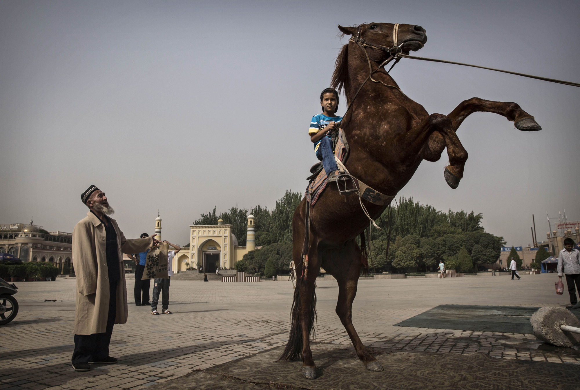 A Uyghur boy sits atop a horse as he has his picture taken outside the Id Kah Mosque before the Eid holiday on July 28, 2014 in old Kashgar.