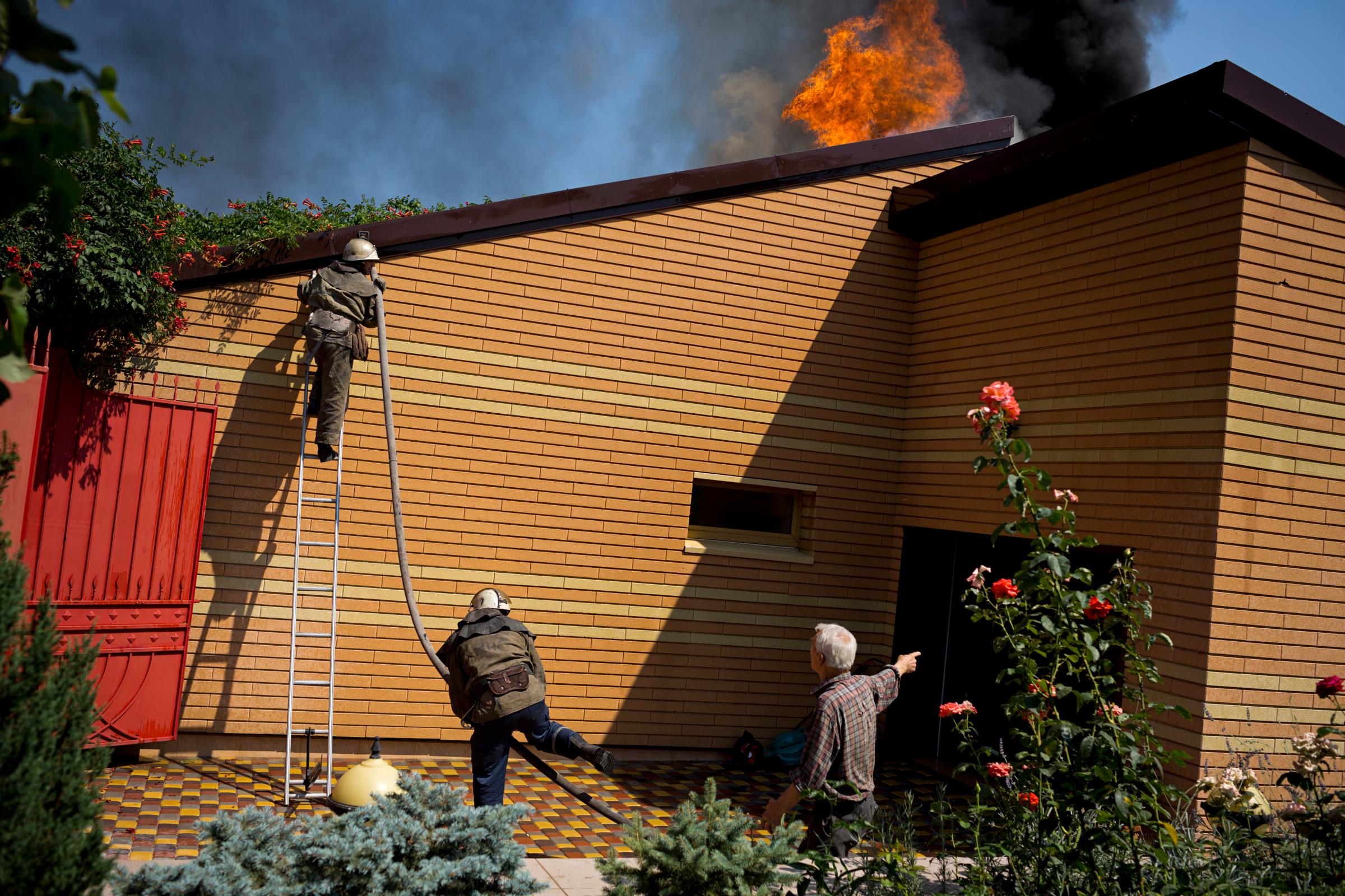 Firemen try to put out a fire in Voroshyloskyi, a residential area of Donetsk, after it was hit by artillery shelling on August 14, 2014 in Ukraine.