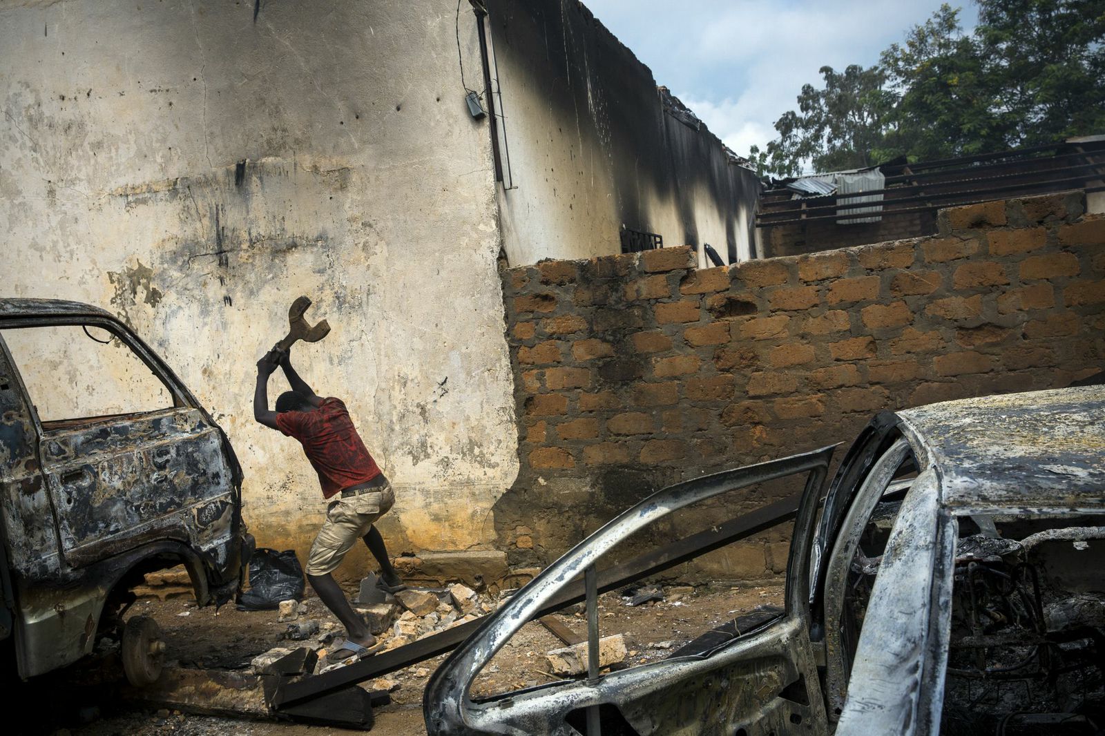 A Christian man is destroying burn out cars in rage, next to a looted mosque that was set on fire earlier, in the Central African Republic's capital Bangui.