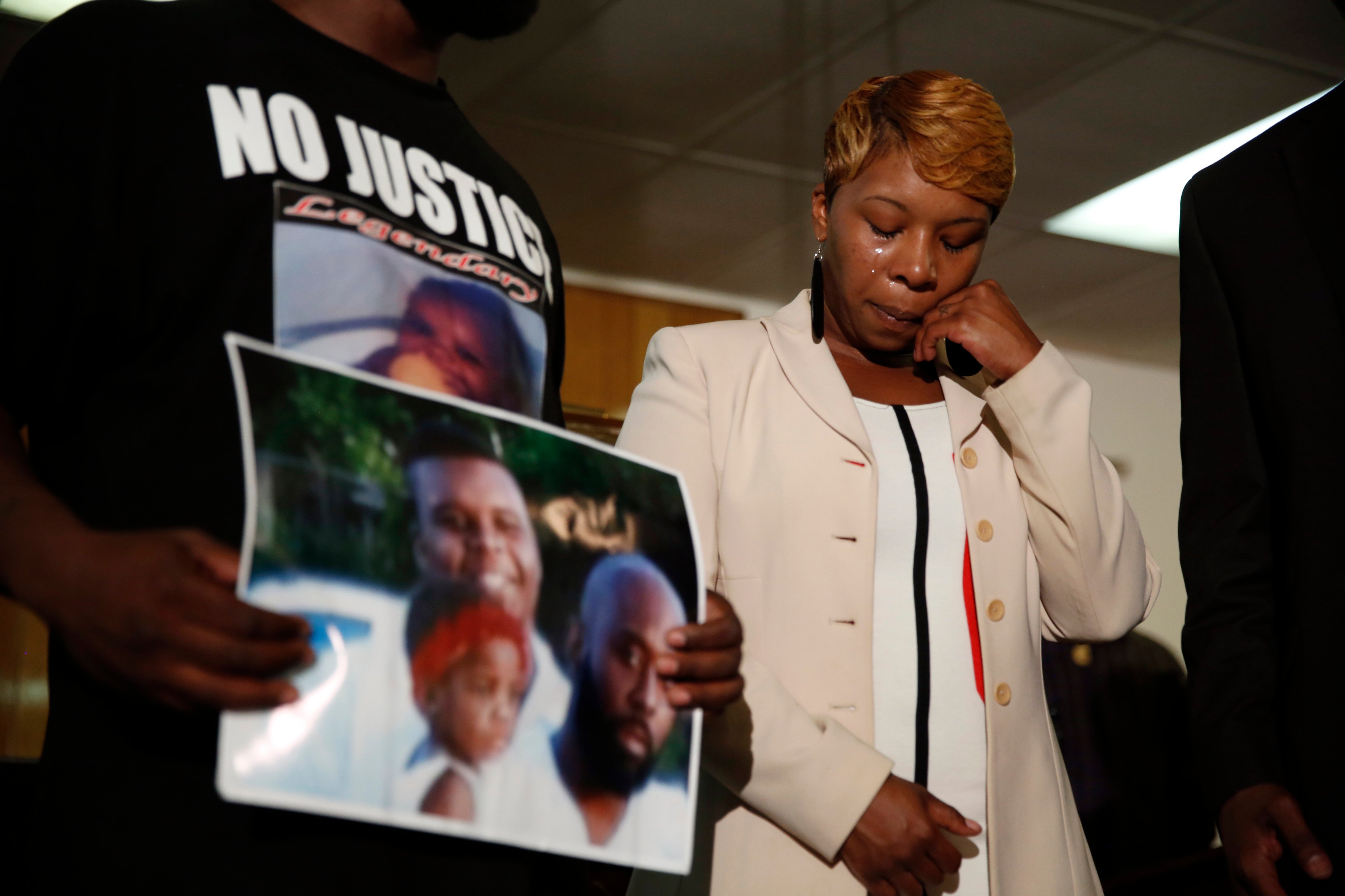 Lesley McSpadden, the mother of 18-year-old Michael Brown, wipes away tears as Brown's father, Michael Brown Sr., holds up a family picture of himself and his son during a news conference on August 11, 2014, in Ferguson, Mo. (Jeff Roberson—AP)