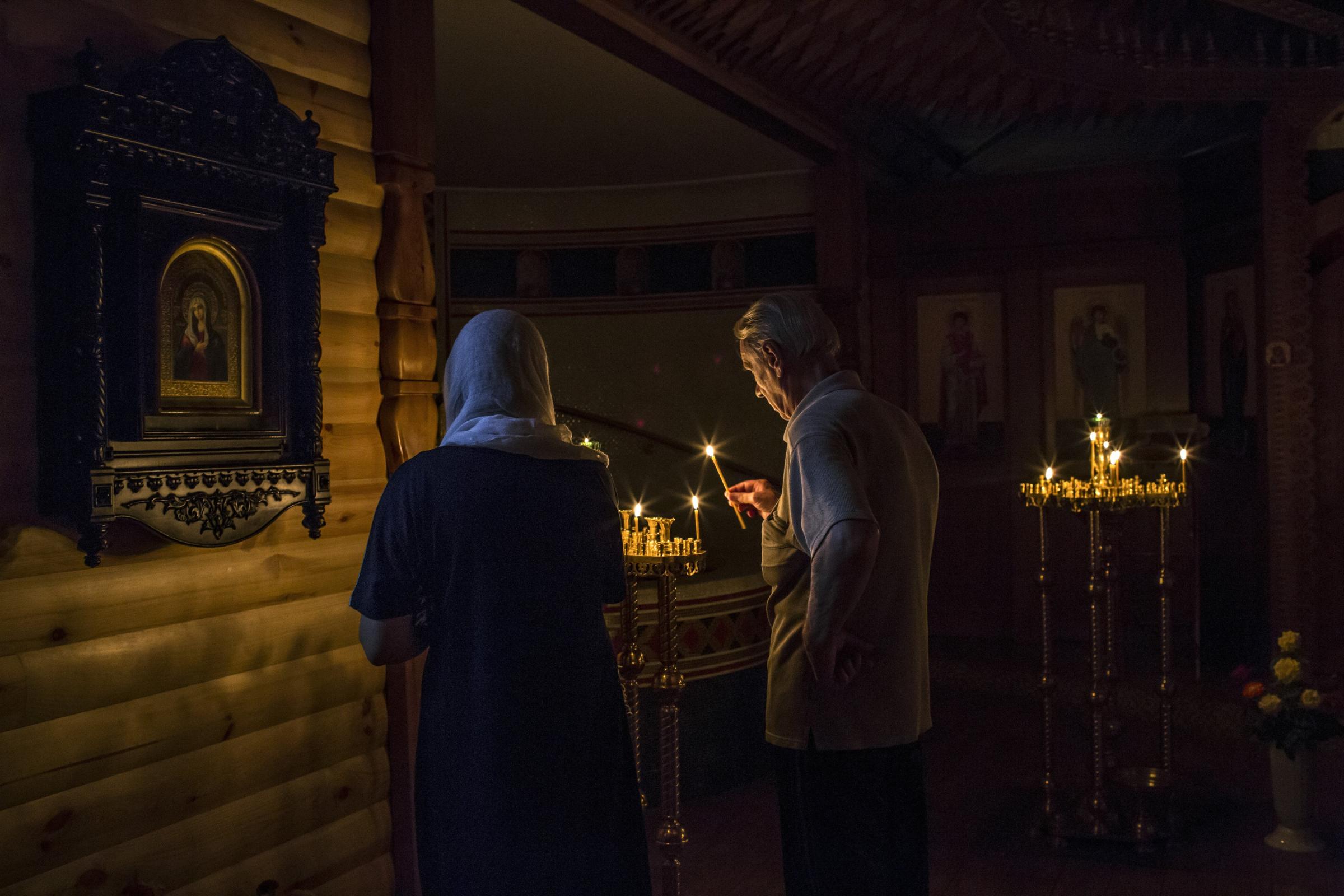 A couple lights a candle as they pray in a lower room of a church which was reportedly damaged by shelling in Luhansk, Ukraine on August 14, 2014.