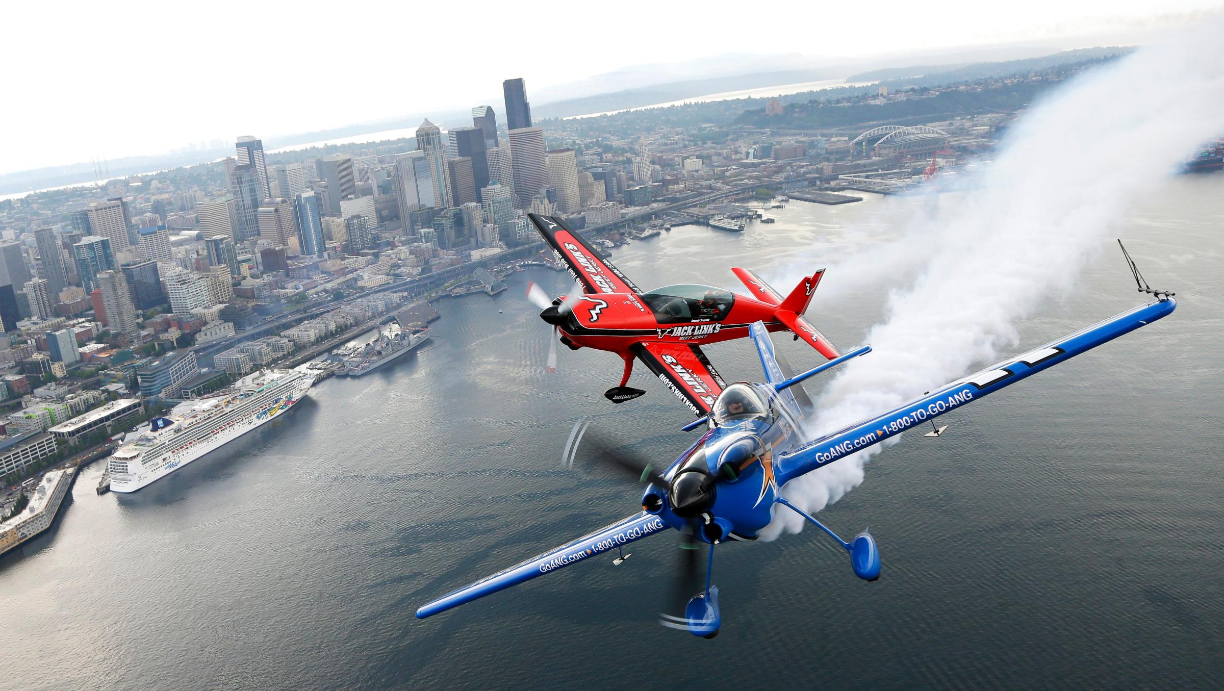Pilots John Klatt, right, flying the blue Air National Guard MX-S airplane, and Jeff Boerboon, left, flying the red Jack's Links Extra 300L airplane, fly in formation above Seattle on Aug. 2, 2014.