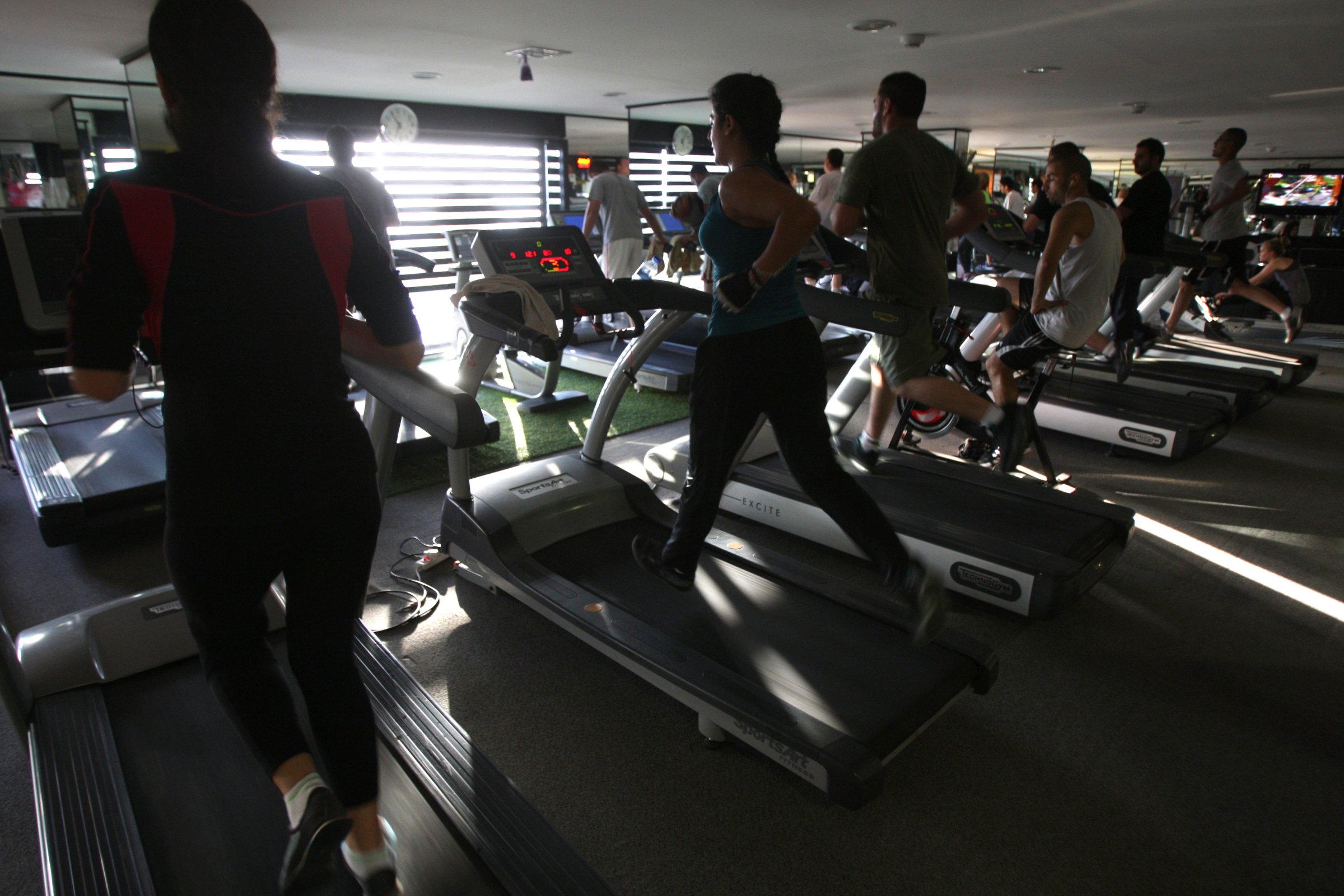 Men and women run on treadmills at a fitness gym in the West Bank city of Ramallah on June 25, 2012.