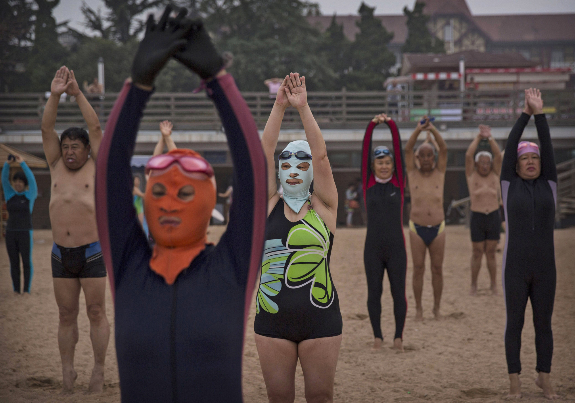 Women wear face-kinis as they exercise on the beach on Aug. 20, 2014 on the Yellow Sea in Qingdao.