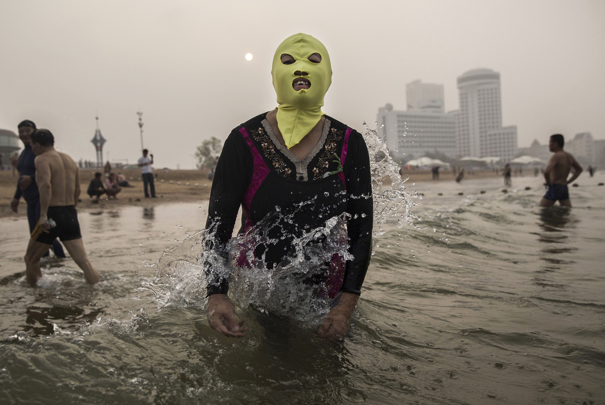 A woman wears a face-kini as she gets wet before swimming on Aug. 22, 2014 on the Yellow Sea in Qingdao.