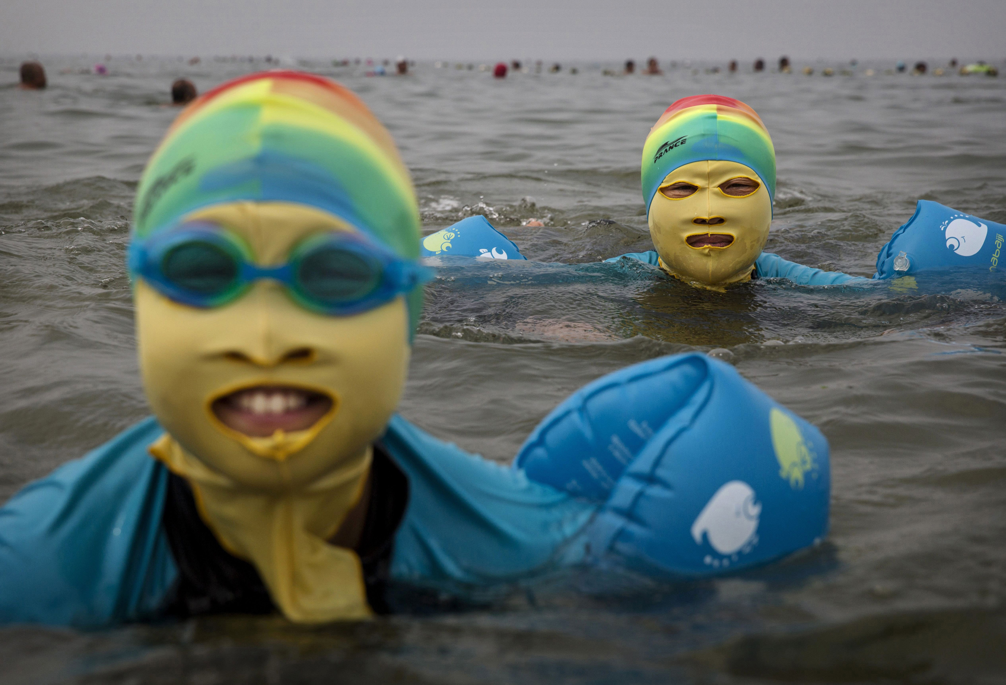 A woman and her daughter wear facekinis while swimming on Aug. 22, 2014, in the Yellow Sea in Qingdao.