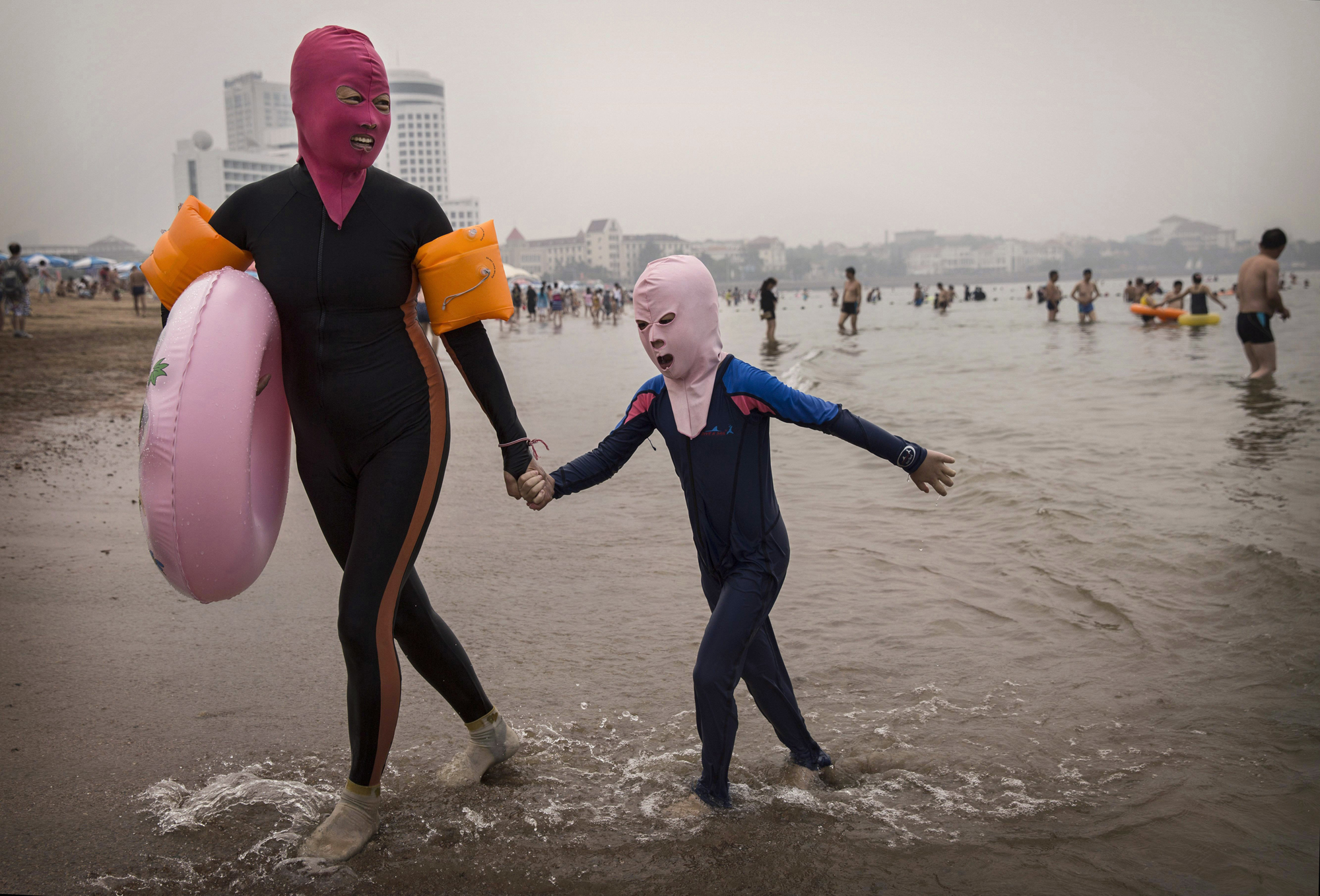 A woman and her daughter wear facekinis as they leave the water at the beach on Aug. 21, 2014, on the Yellow Sea in Qingdao.