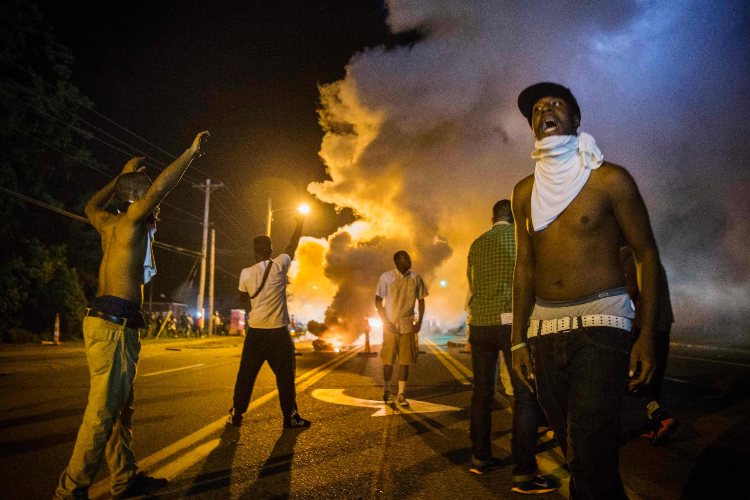 Demonstrators stand in the middle of West Florissant as they react to tear gas fired by police during ongoing protests in reaction to the shooting of Brown, near Ferguson