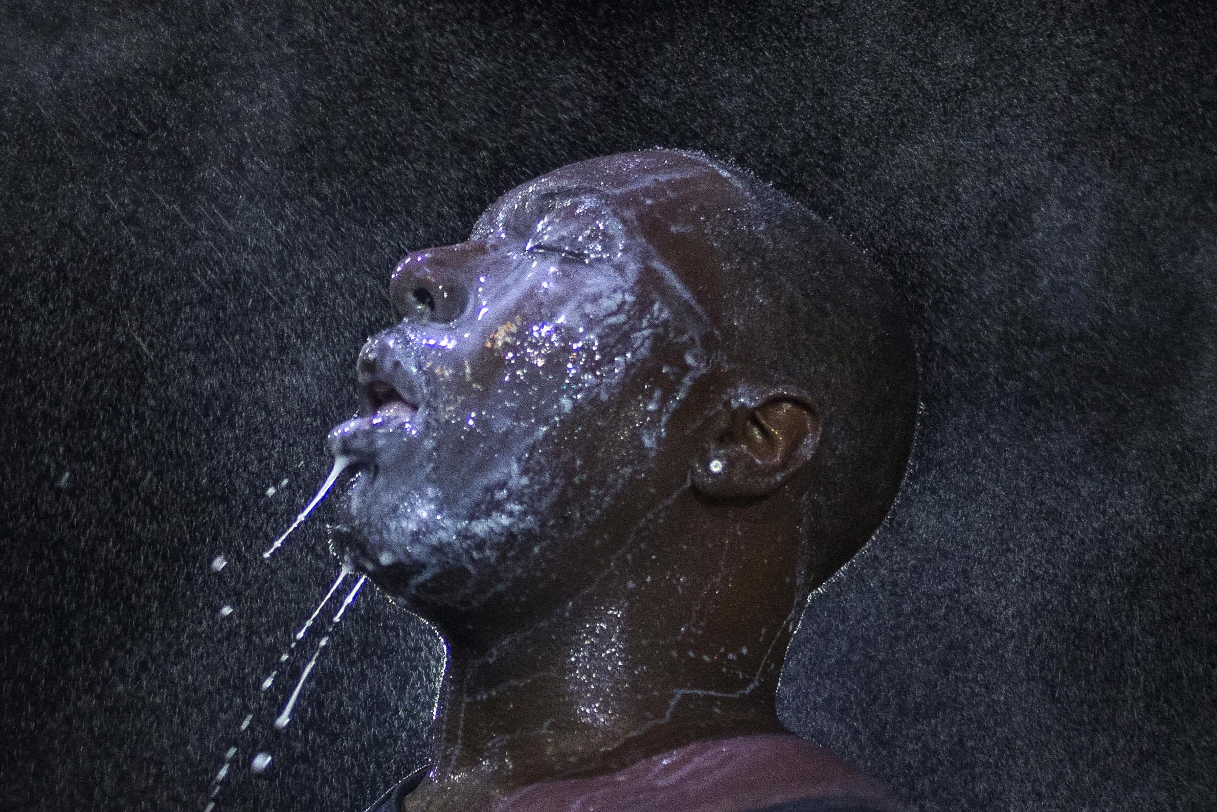 A man is doused with milk and sprayed with mist after being hit by an eye irritant from security forces trying to disperse demonstrators protesting against the shooting of Brown in Ferguson