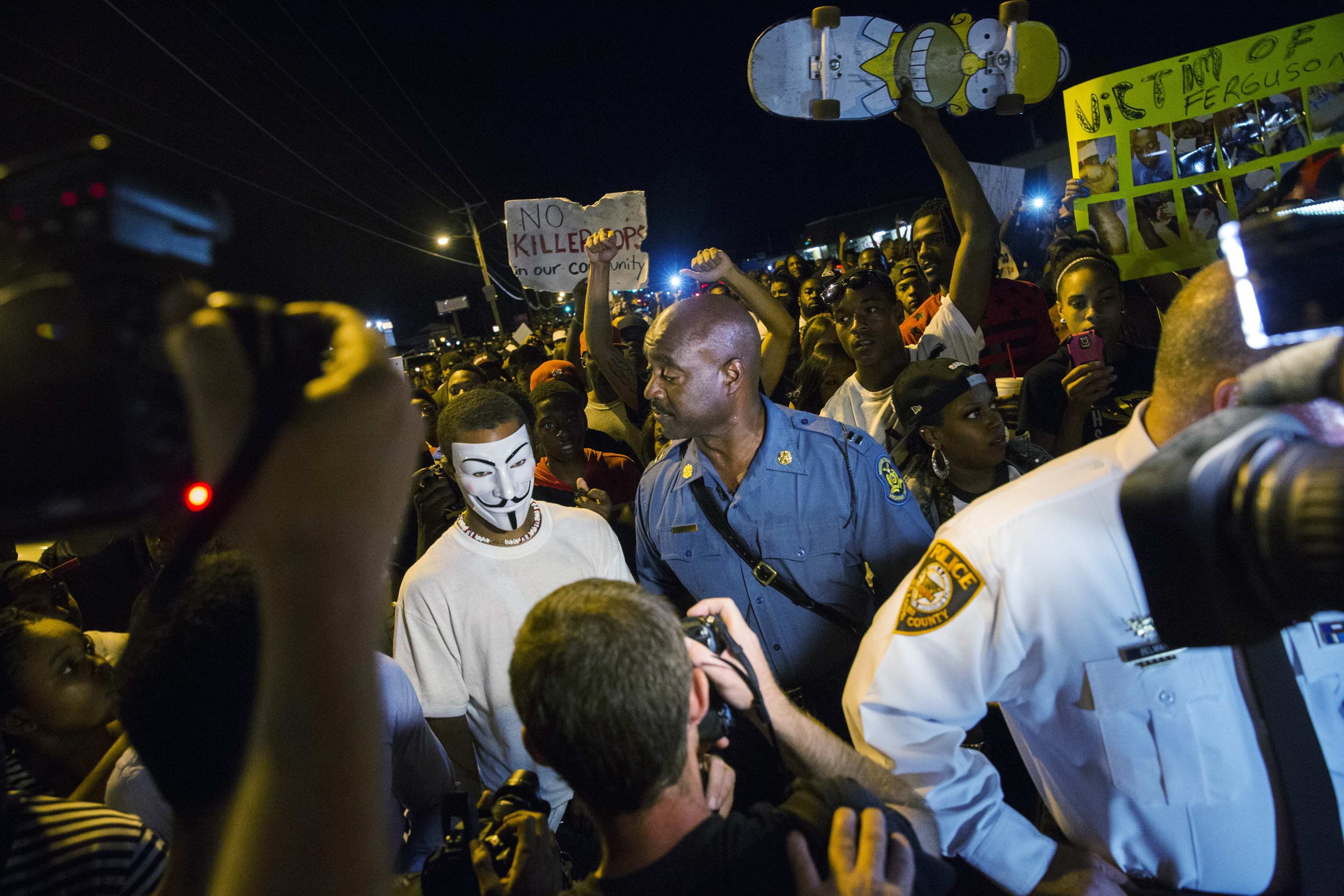 Ron Johnson of Missouri State Highway Patrol speaks to a protester wearing a Guy Fawkes mask while he walks through a peaceful demonstration in Ferguson, Mo., on Aug. 14, 2014 (Lucas Jackson—Reuters)