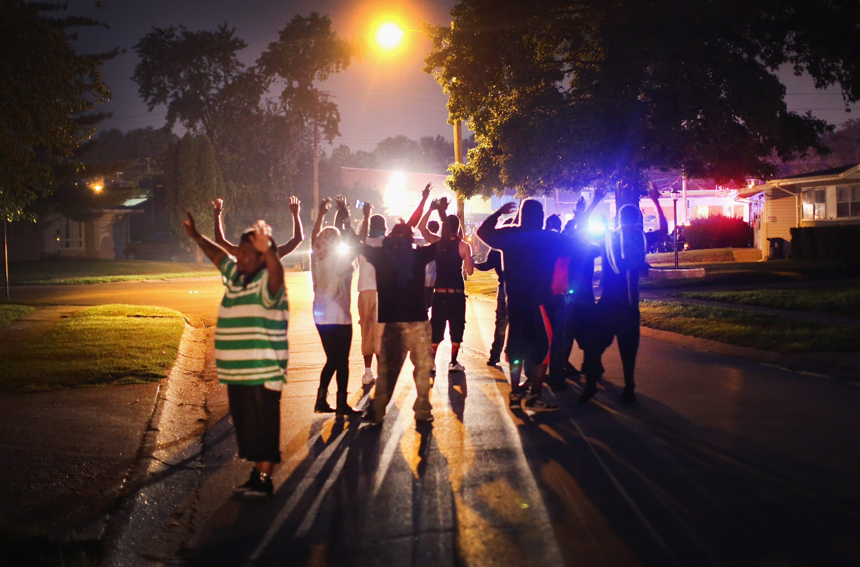With their hands raised, residents gather at a police line as the neighborhood is locked down following skirmishes on August 11, 2014 in Ferguson, Missouri. (Scott Olson—Getty Images)