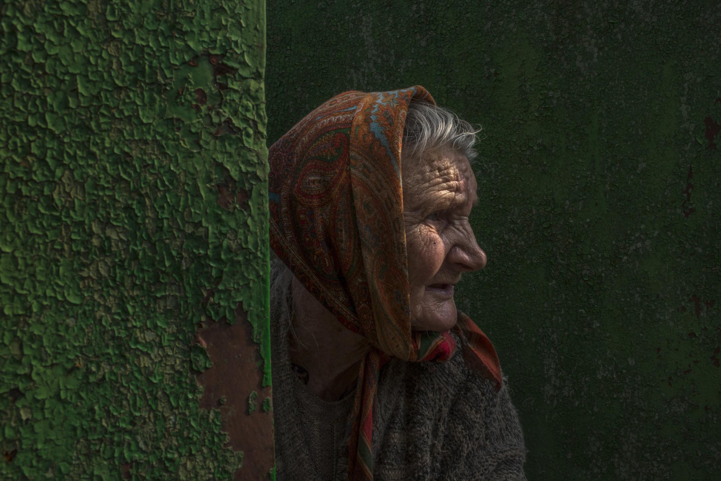 Nadezda Ivanovna peers through the gate of her home, on the outskirts of Slovyansk, Ukraine.