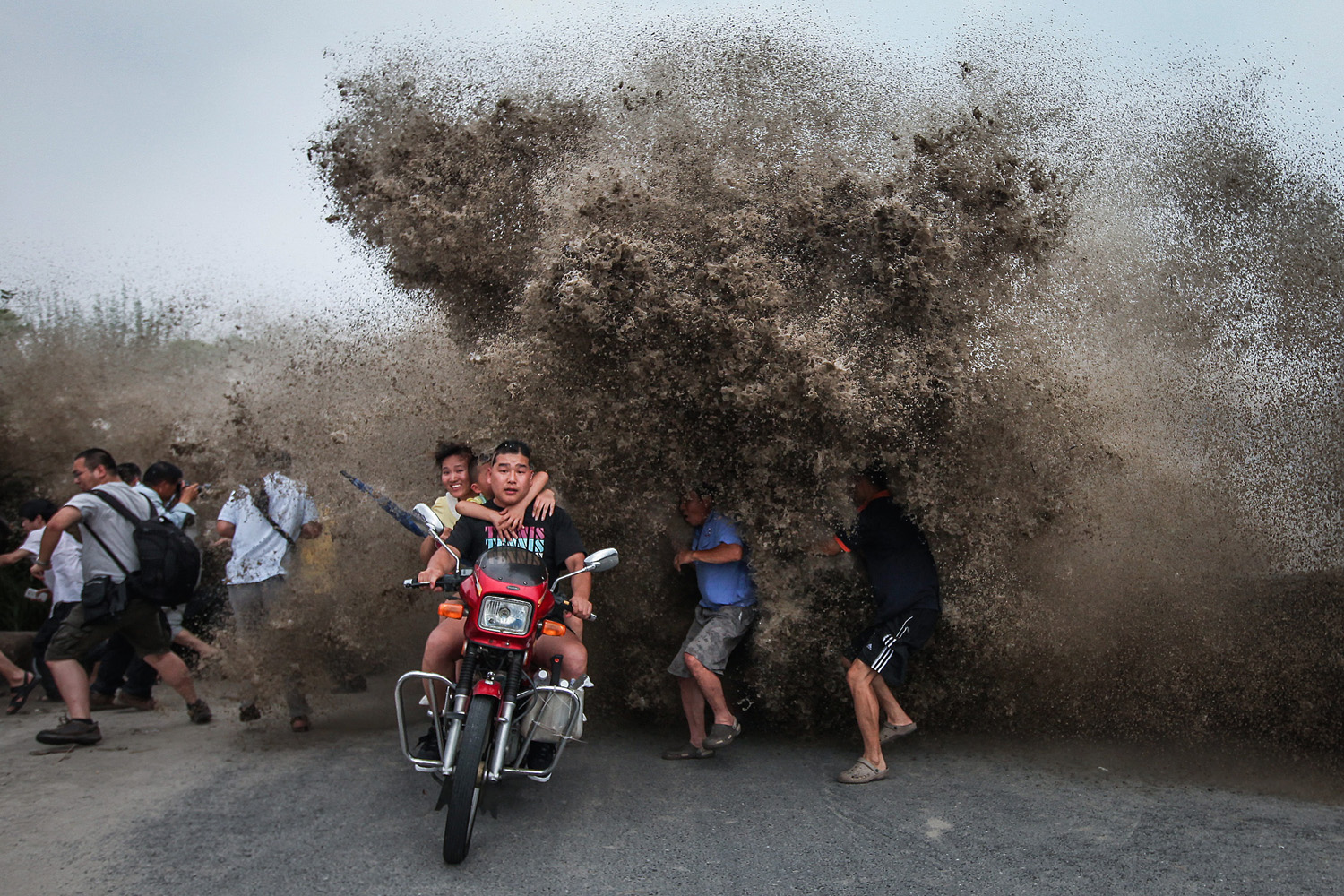 Tidal wave spectators react to a high wave hitting the bank of Qiantang River in Hangzhou, Zhejiang province, China on August 13, 2014.