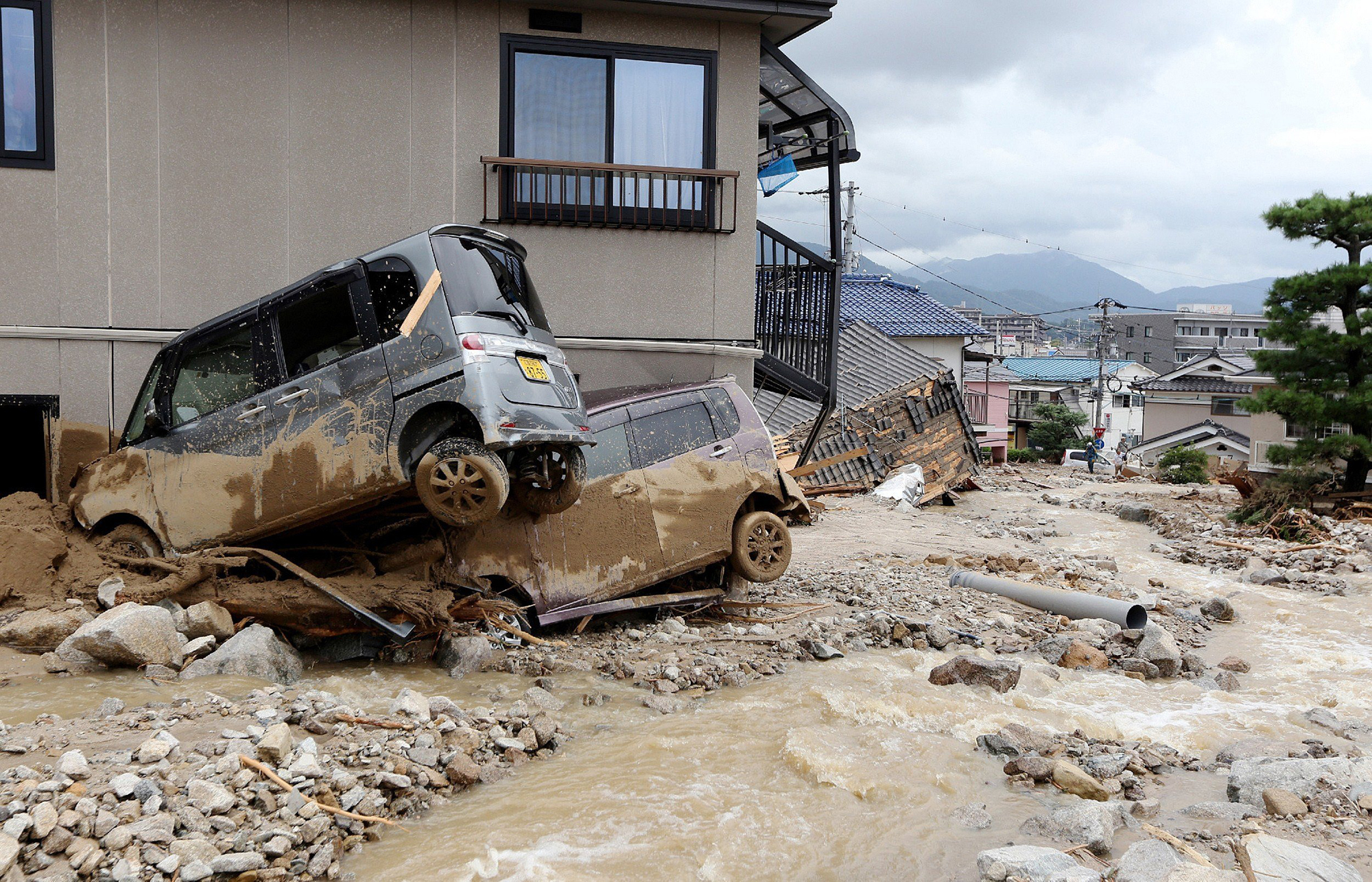 Cars damaged by a landslide lie in mud and debris after heavy rains hit the city of Hiroshima, western Japan, on Aug. 20, 2014.