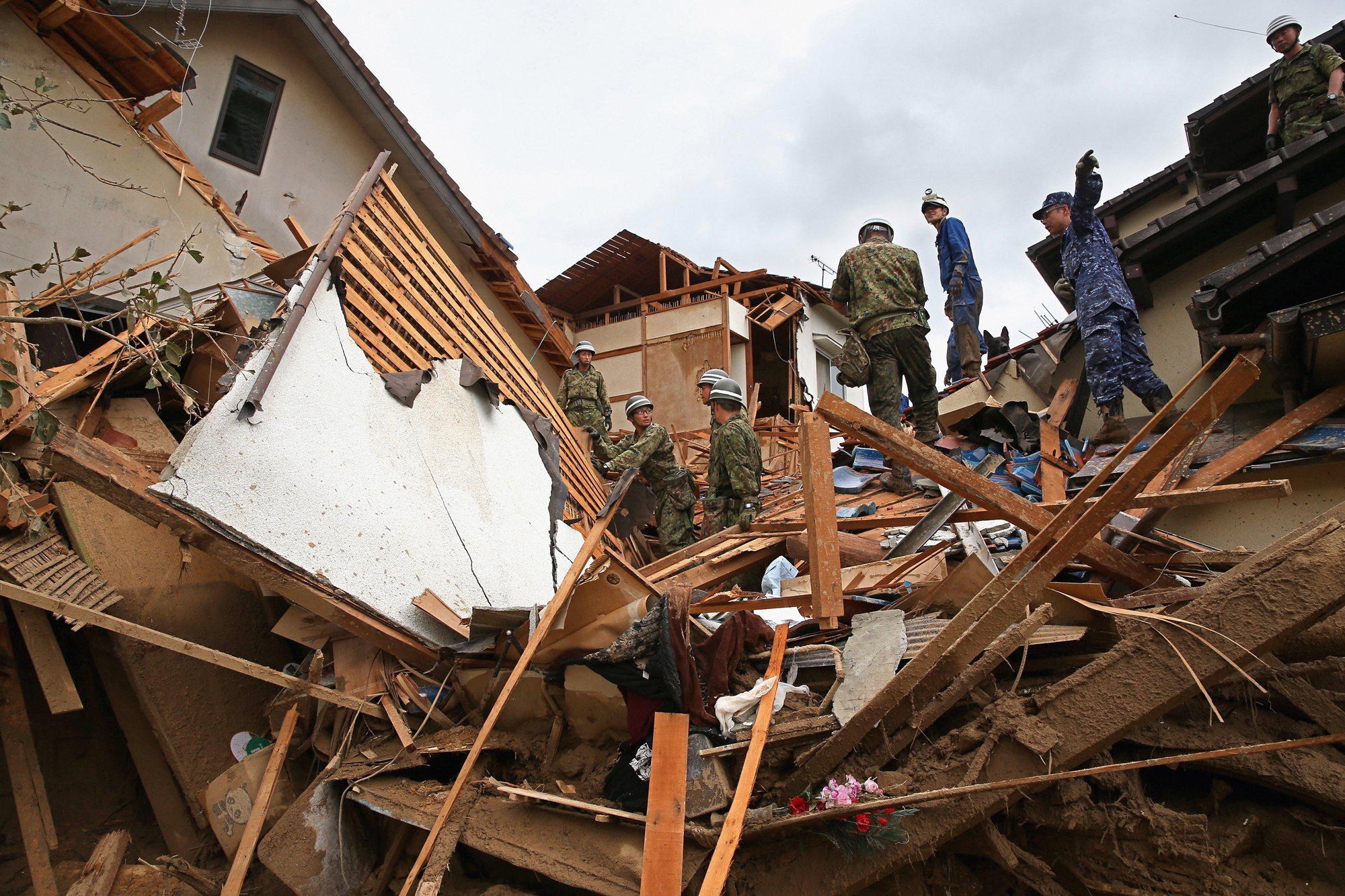 Japan Ground Self-Defense Force members conduct rescue operations at a destroyed house after landslides on Aug. 20, 2014 in Hiroshima, Japan.