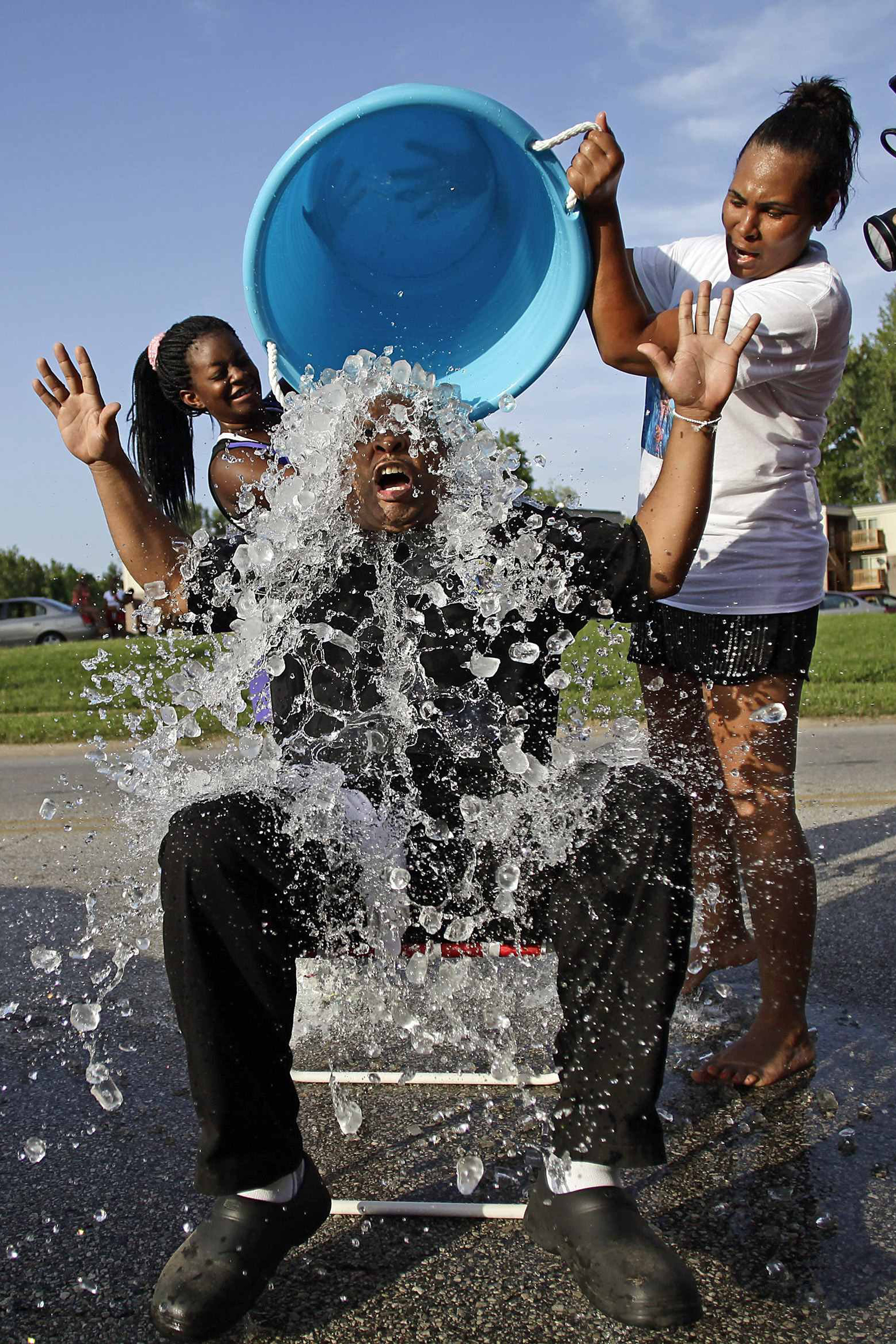 Supporters of Michael Brown, Kalisha Gilmore (L) and Recorida Kennedy (R), pour ice water on Kevin Ephron as he takes the ice bucket challenge in remembrance of Brown along Canfield Drive, where he was fatally shot by a police officer in Ferguson, Missouri August 24, 2014. 