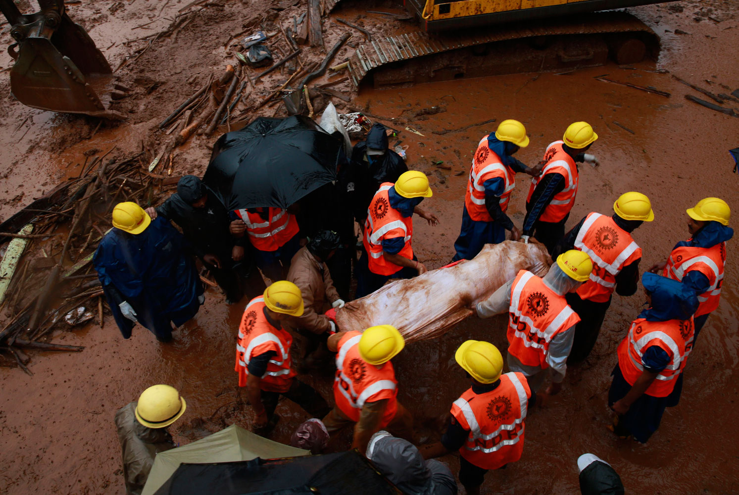 Rescue workers carry the body of a victim after a massive landslide in Malin village in Pune district of western Maharashtra state, India on July 31, 2014. Two days of torrential rains triggered the landslide early Wednesday, killing more than two dozen people and trapping more than 150, authorities said.