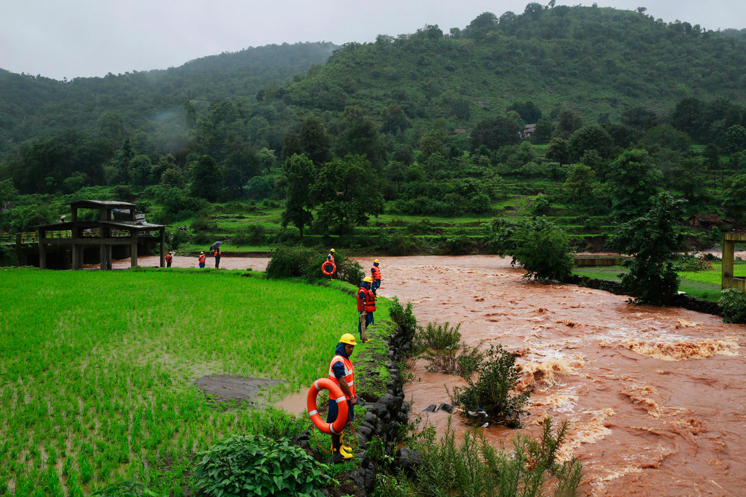 Rescue workers stand on the bank of a river as they look for bodies after a massive landslide in Malin village in Pune district of western Maharashtra state, India on July 31, 2014.