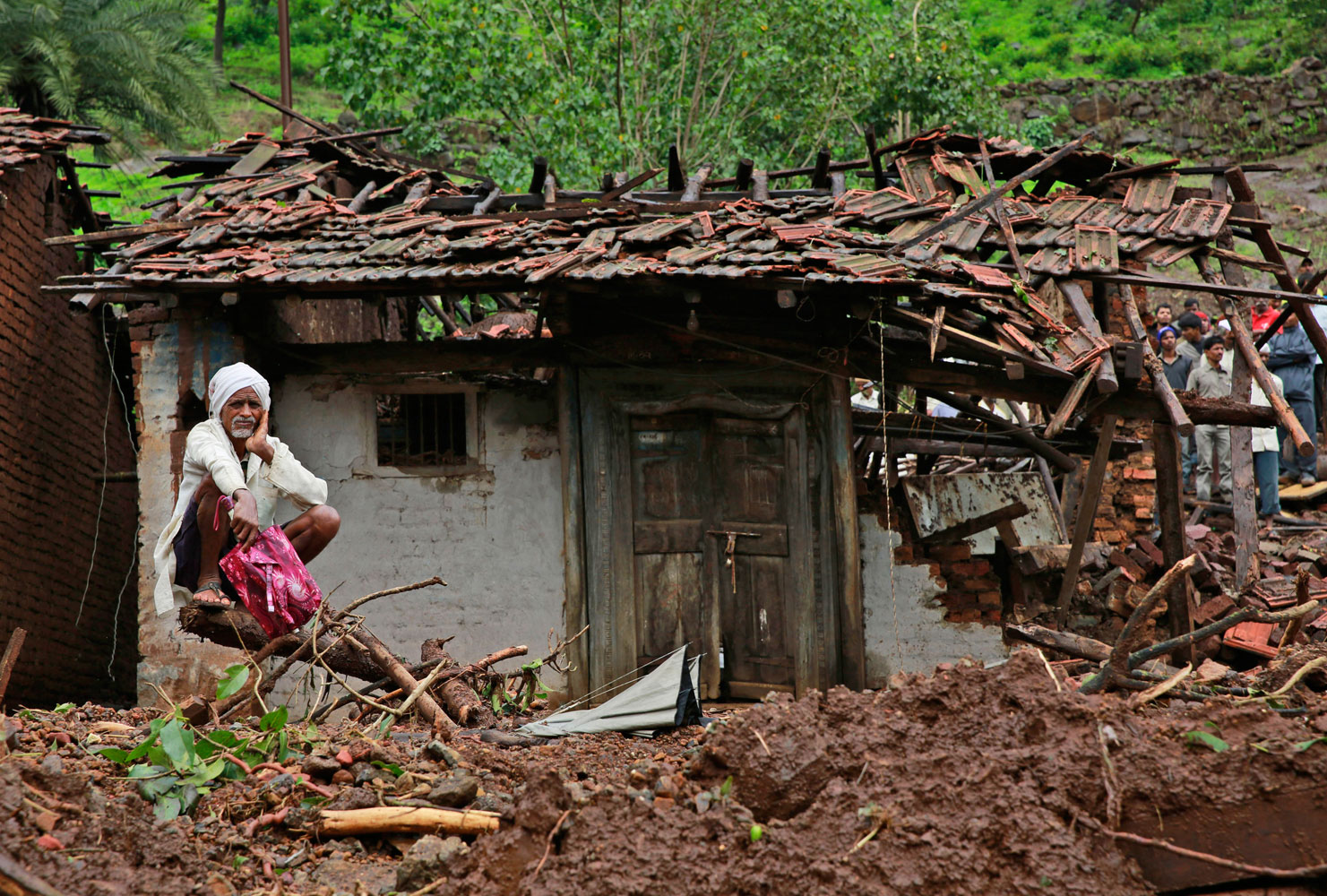 A villager watches a rescue operation sitting by his damaged house at the site of a landslide in Malin village, in the western Indian state of Maharashtra on Aug. 1, 2014.