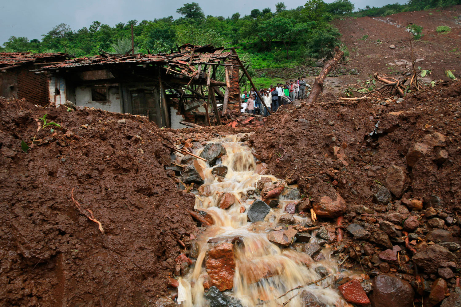 Villagers watch a rescue operation standing by mud and slush at the site of a landslide in Malin village, in the western Indian state of Maharashtra on Aug. 1, 2014.