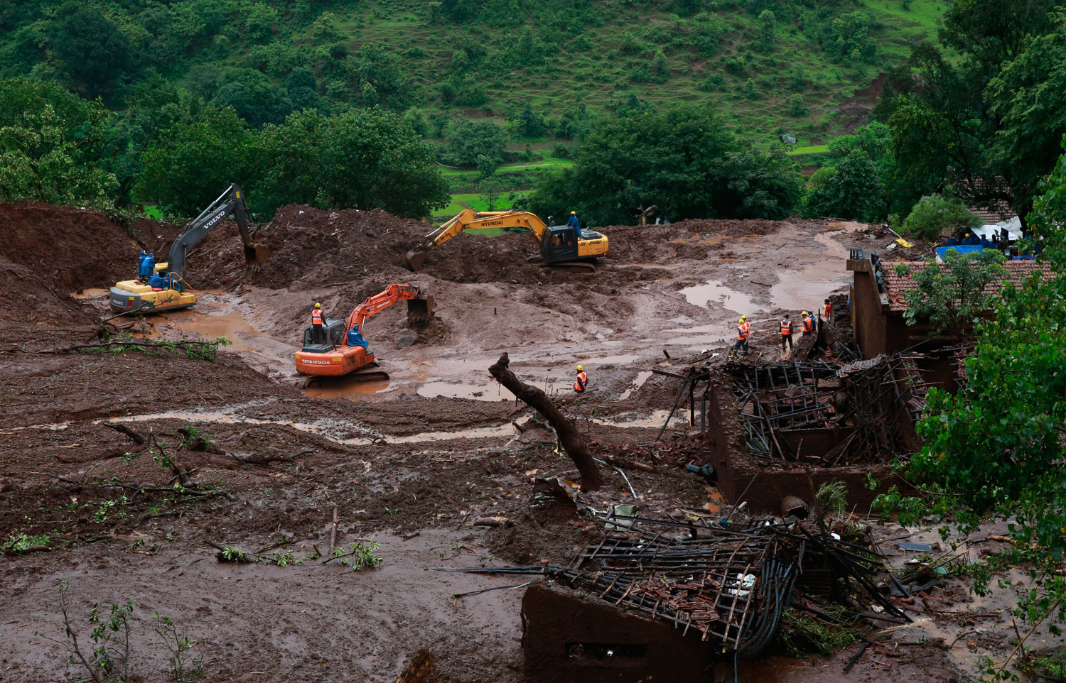 Earthmovers clear mud and slush at the site of a landslide in Malin village, in the western Indian state of Maharashtra on Aug. 1, 2014.