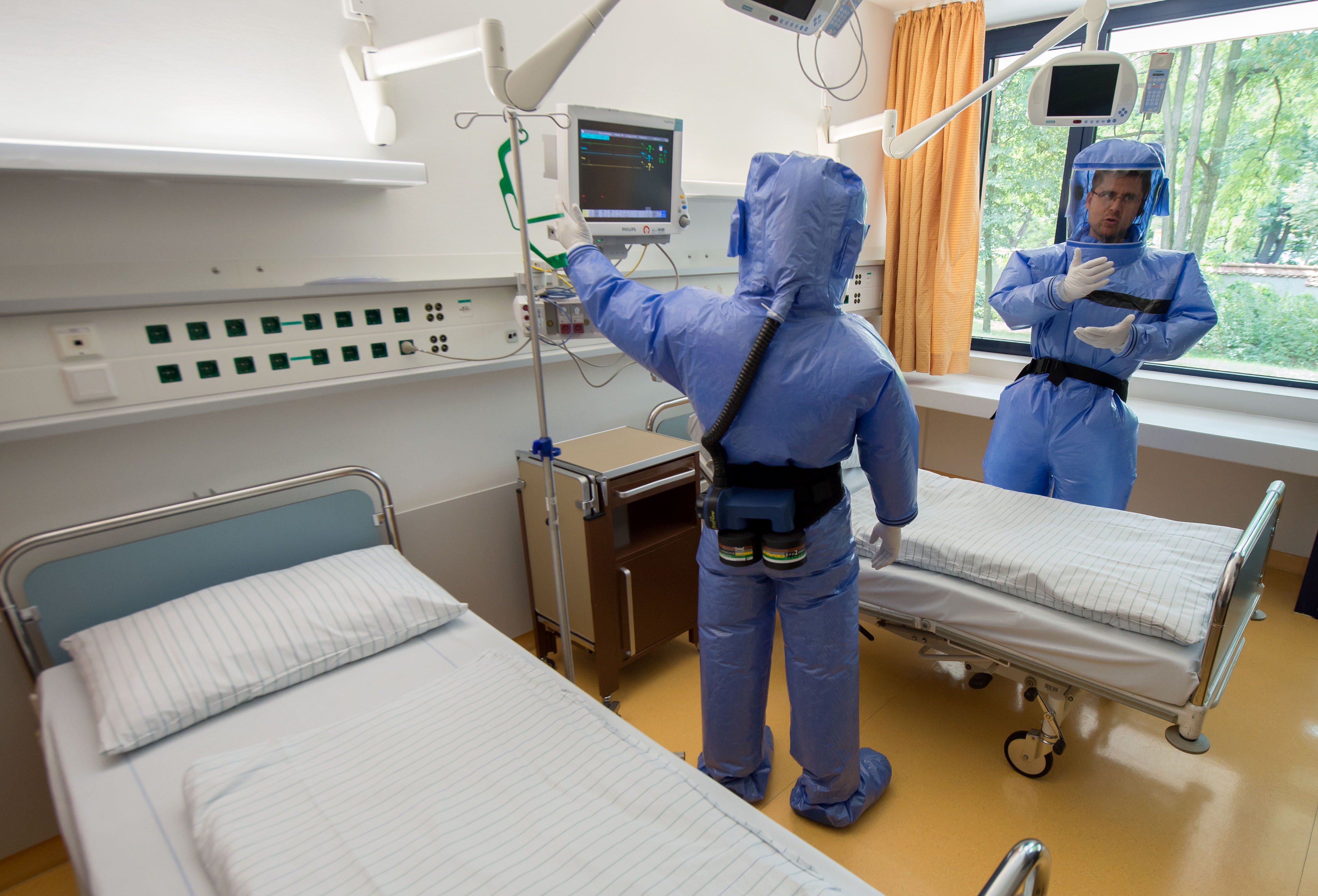 Infectious disease specialist Florian Steiner and quarantine office leader Thomas Klotzkowski wear protective clothing as they stand in a sick room during a demonstration of the proceedings at the ward of Berlin's Charite hospital on August 11, 2014.