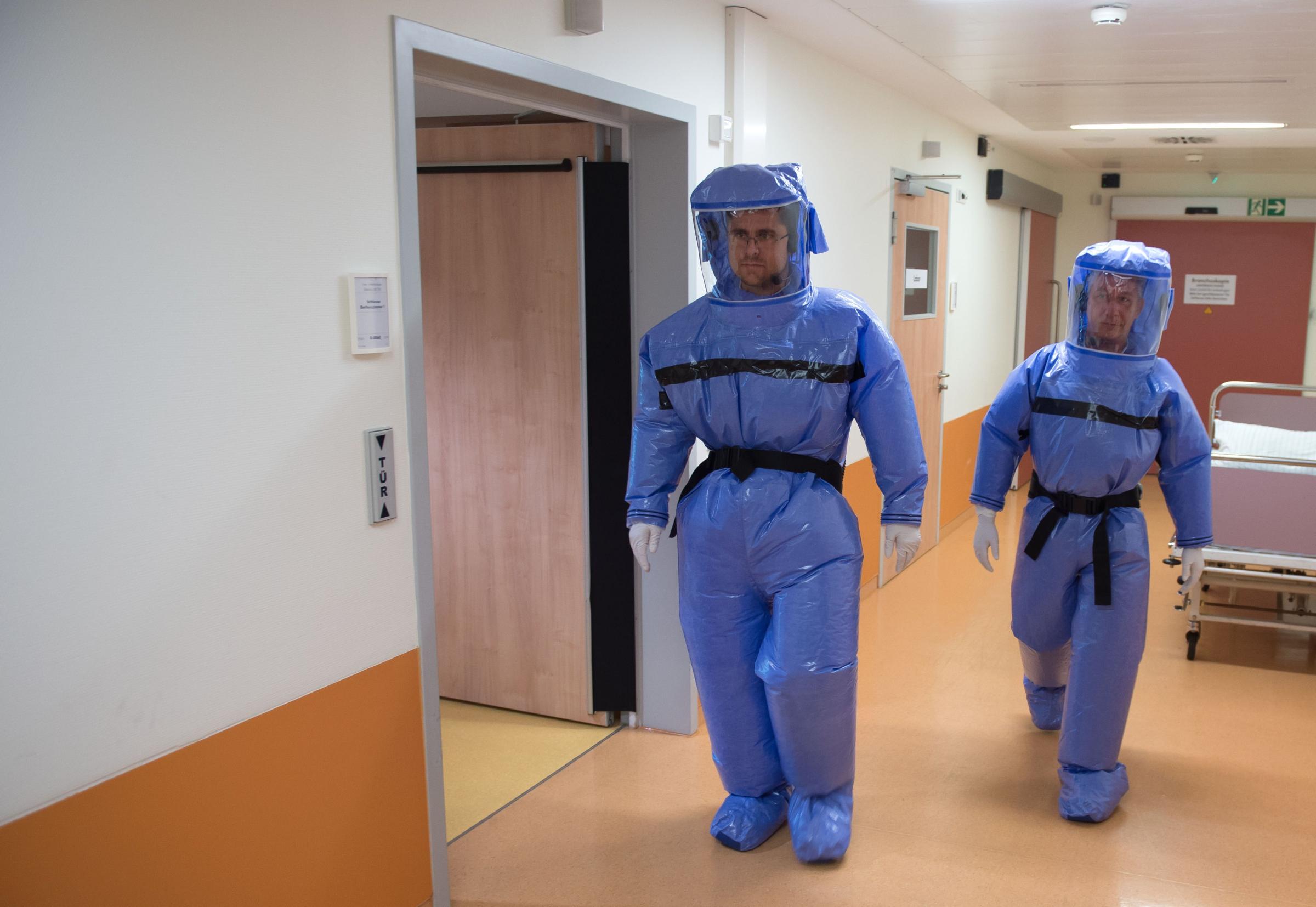 Infectious disease specialist Florian Steiner and quarantine office leader Thomas Klotzkowski wear protective clothing as they demonstrate the proceedings at the ward of Berlin's Charite hospital on August 11, 2014.